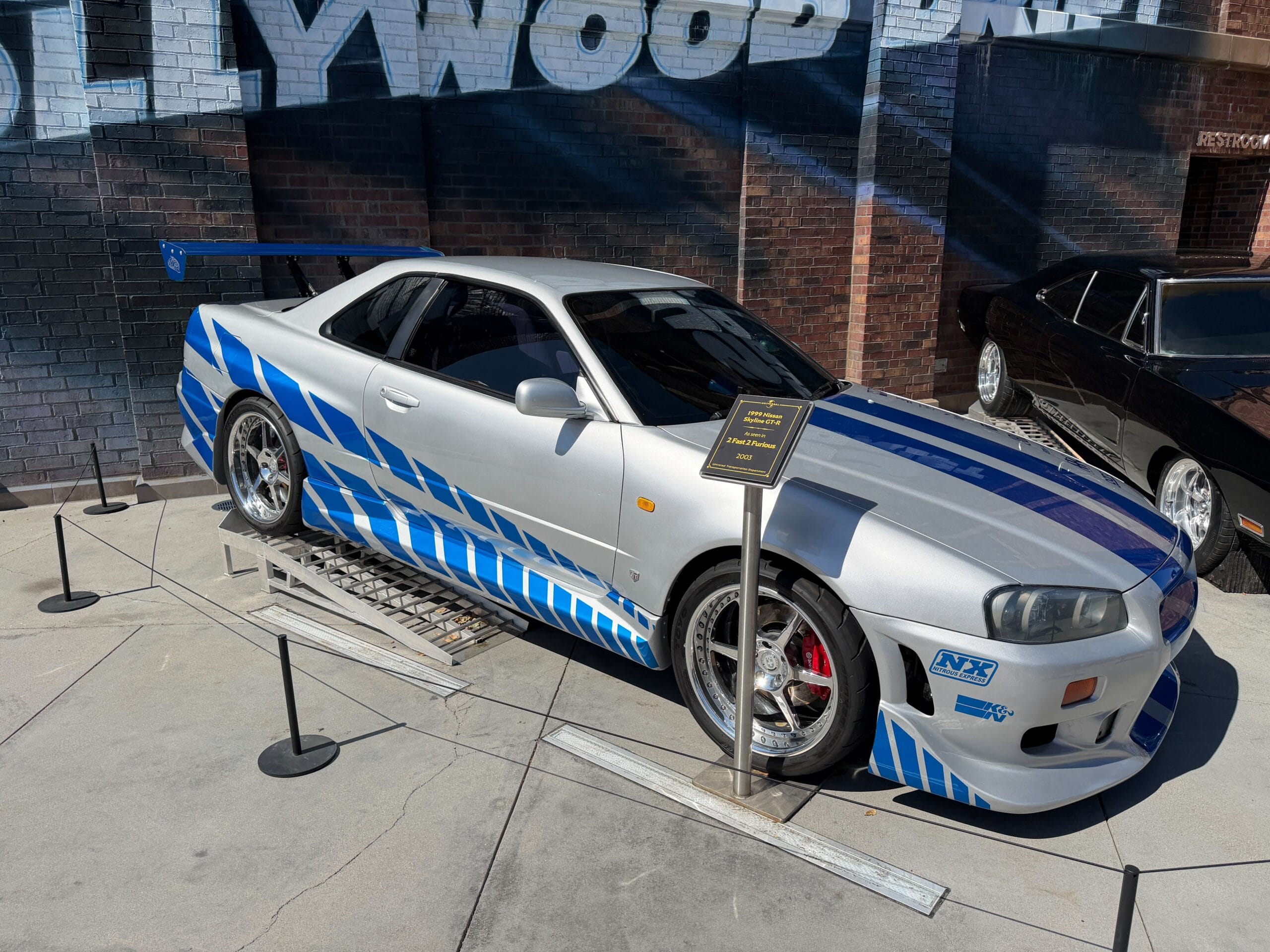 The car on the left is a silver and blue 1999 Nissan Skyline GT-R from the 2003 sequel film, 2 Fast 2 Furious.