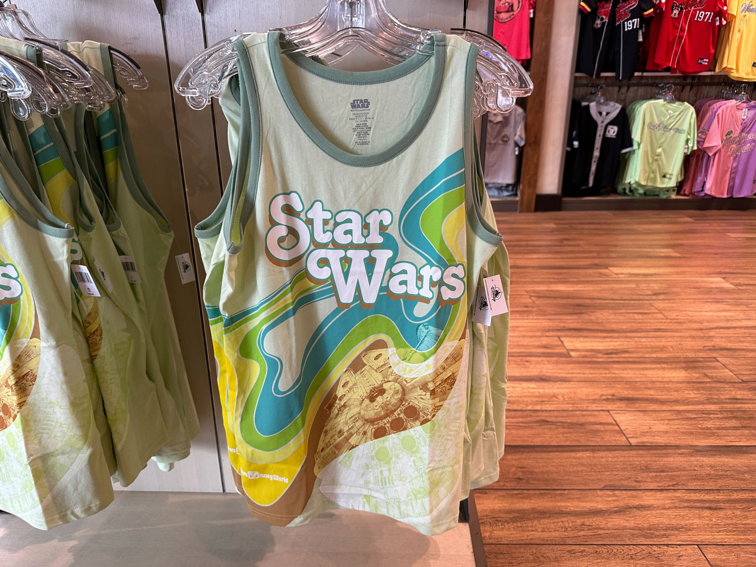 The Star Wars tank is also pale green. Blue, green, yellow, and brown swirls are across the front, crossing over artwork of the Millennium Falcon. "Star Wars" is on the chest.