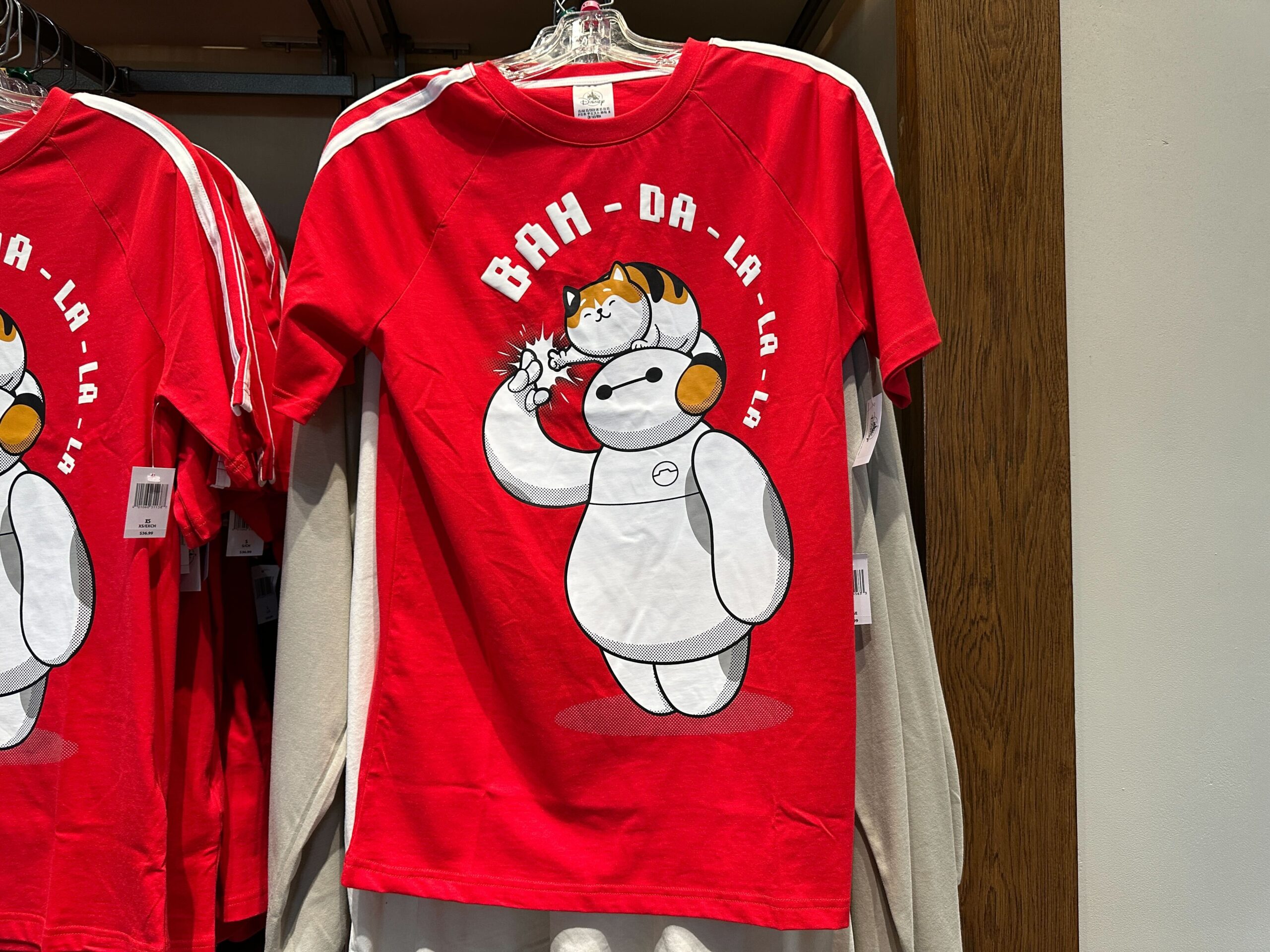 Mochi is perched on Baymax's head and the friends are exchanging a fist bump. "Bah-da-la-la-la" is in pixelated puffy ink letters above them.