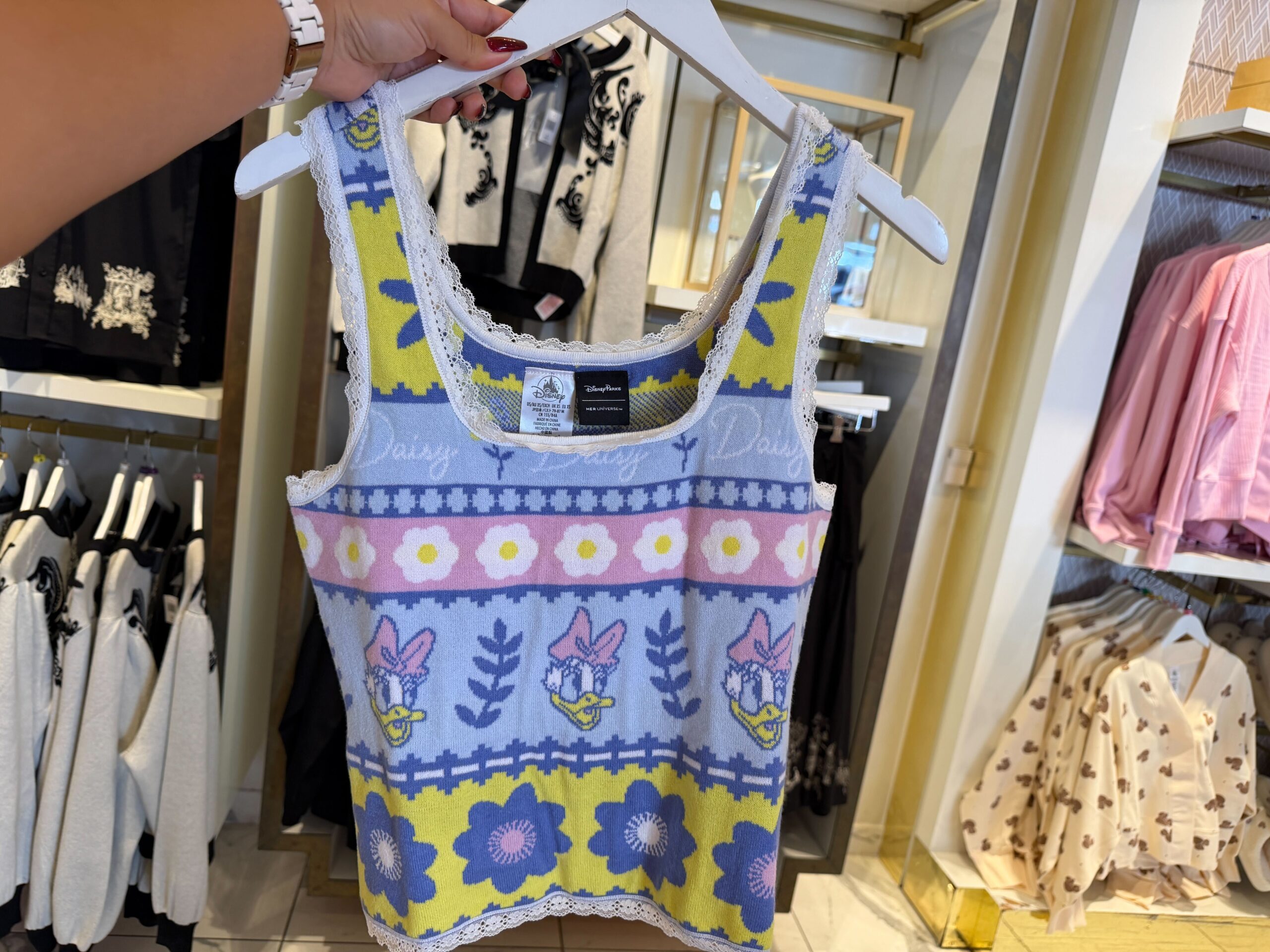 Lastly, the knit tank has neon green, pink, and blue stripes. On each stripe is a design: flowers, "Daisy" text, or Daisy's profile. There is lace on the square neckline and arm holes.