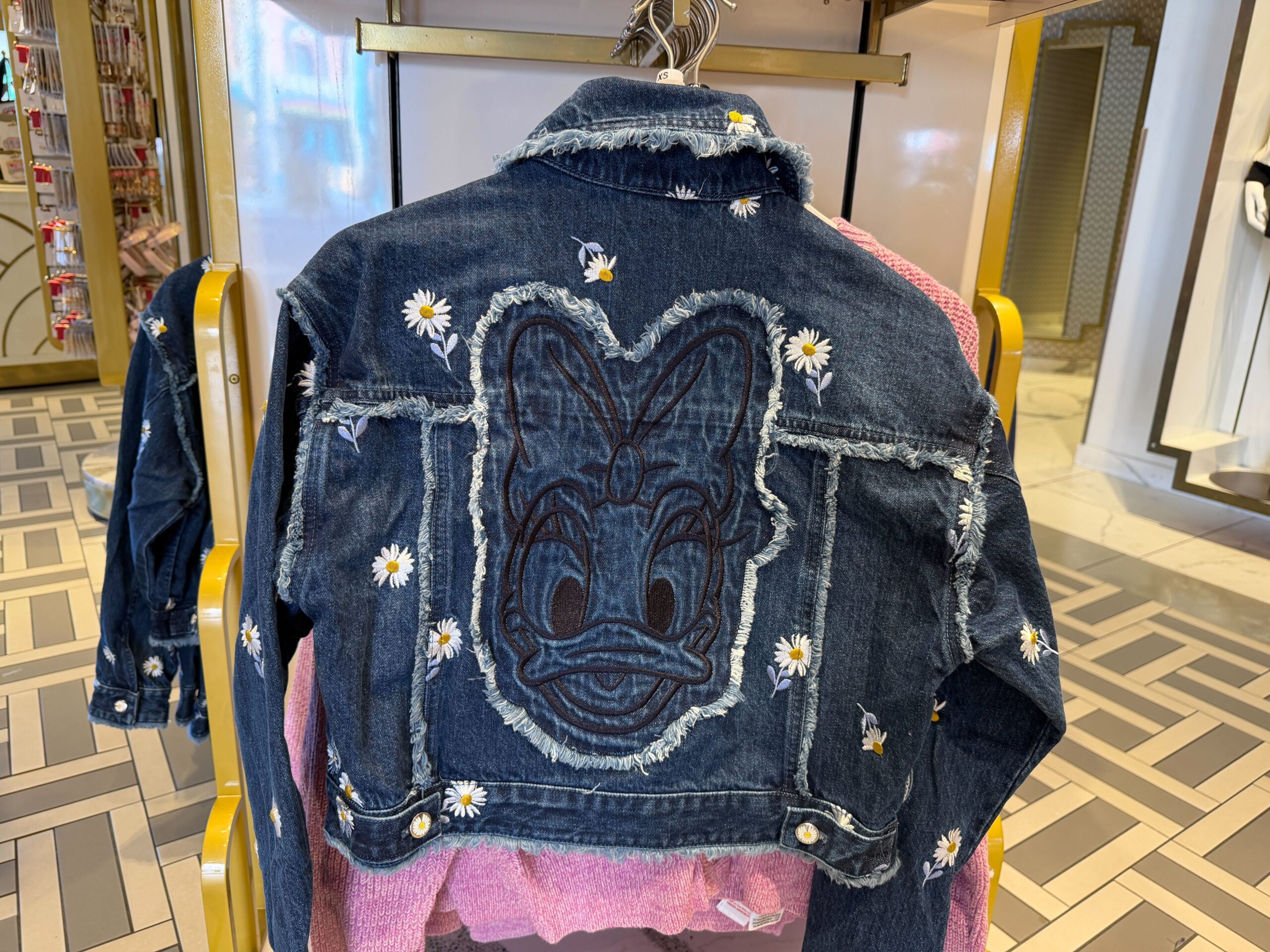 On the back, the fringe details and embroidered daisies continue. A large embroidered outline of Daisy's face is in the center—outlined in more fringe.
