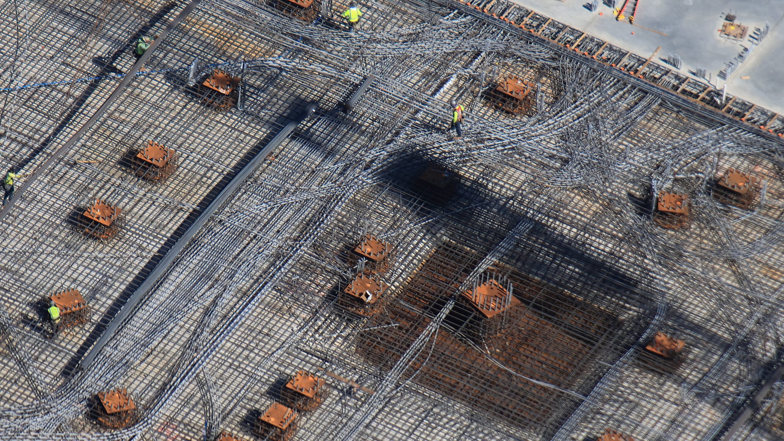 Near the beams, a whole section of conduits and grid is yet to be paved over. There are many raised metal platforms installed here as well. From previous updates, we've seen crews installing elements and covering them section by section.
