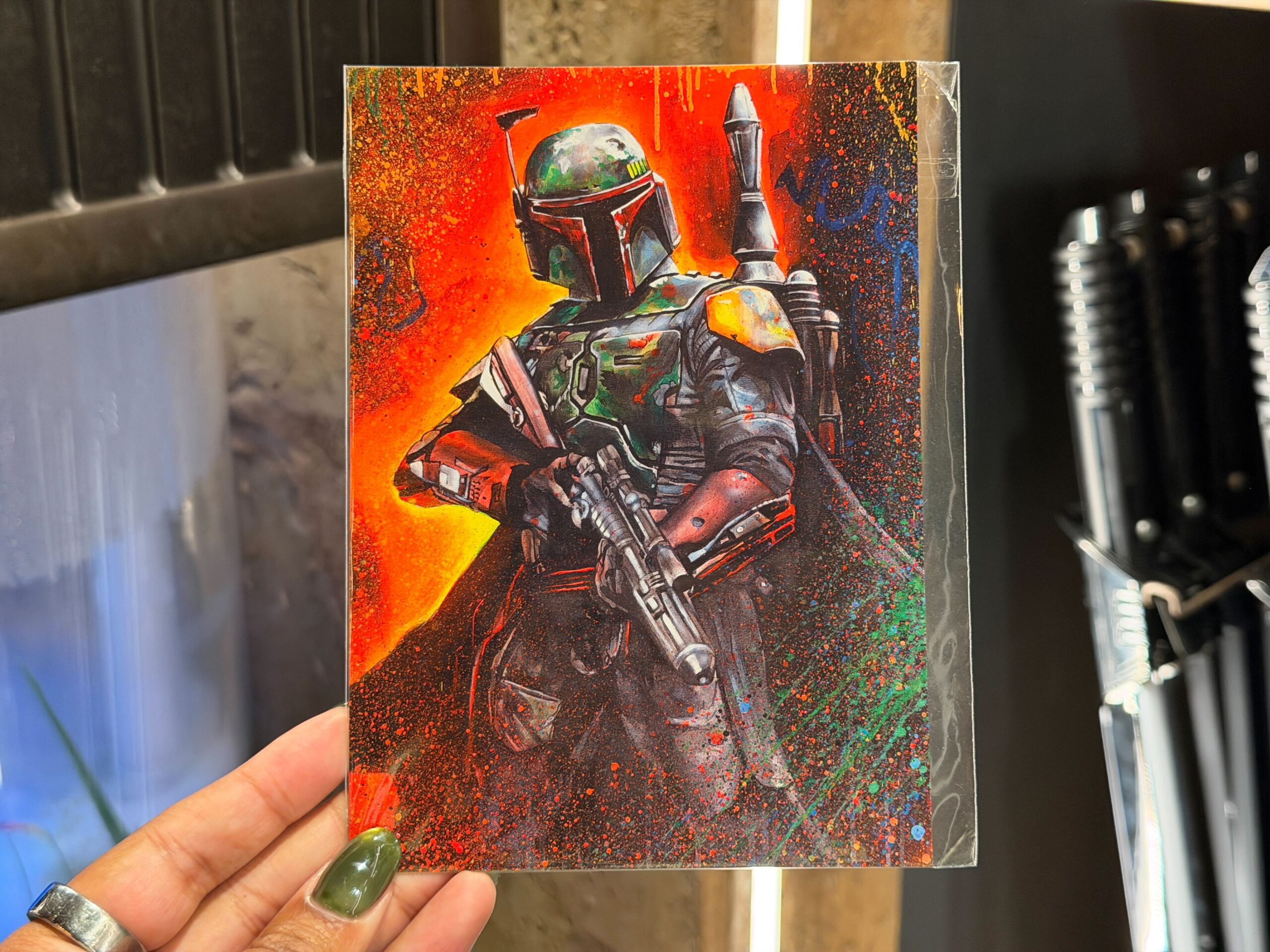A new Boba Fett postcard is also available, featuring vibrant character artwork inspired by the galaxy’s most notorious bounty hunter. The design showcases Boba in bold colors with splatter-style detailing, giving it a gritty, Outer Rim feel.