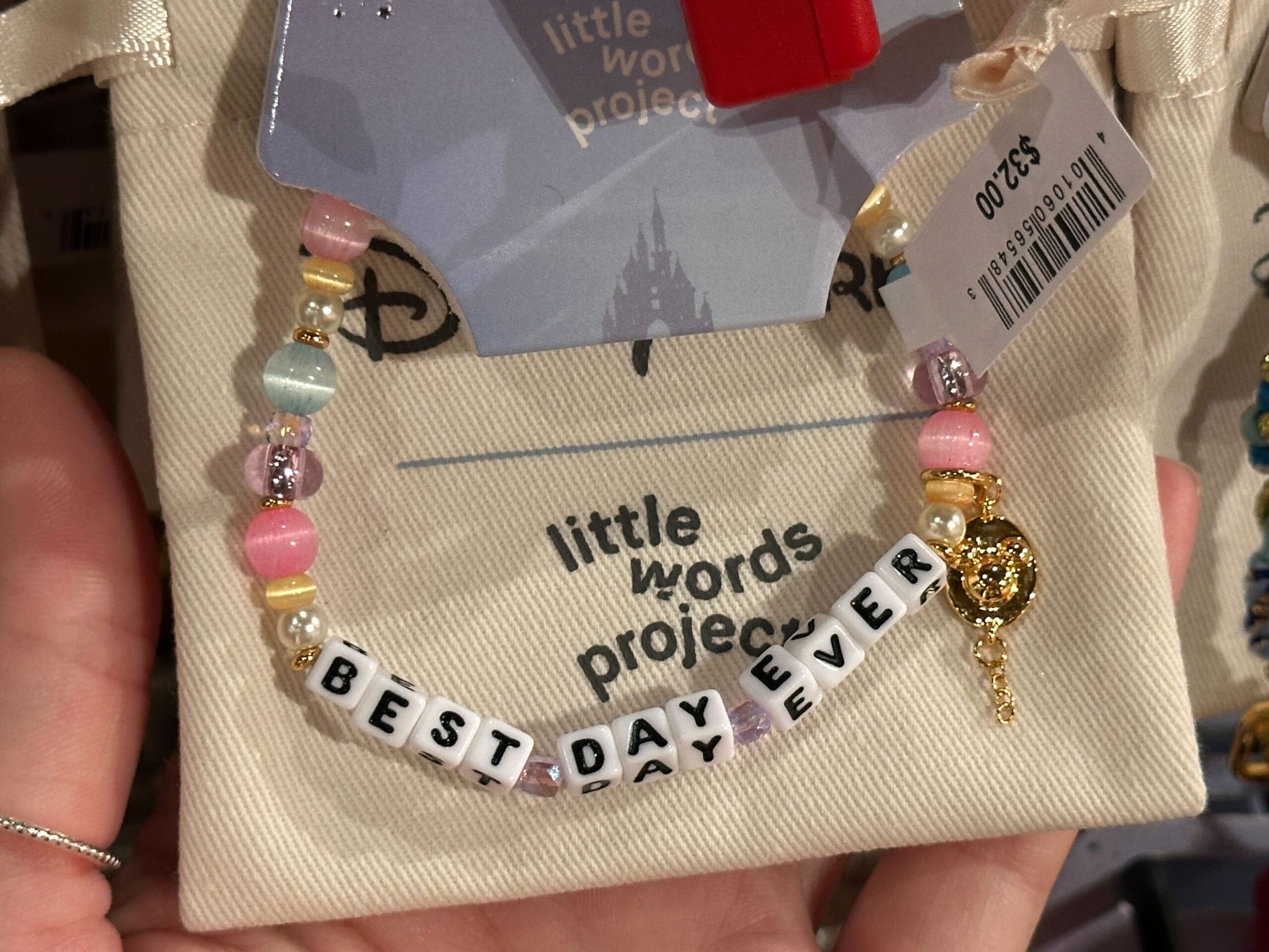 The block letters read “Best Day Ever” with a gold Mickey icon charm on one end. These beads are in shades of light blue, gold, pink, yellow, and ivory.