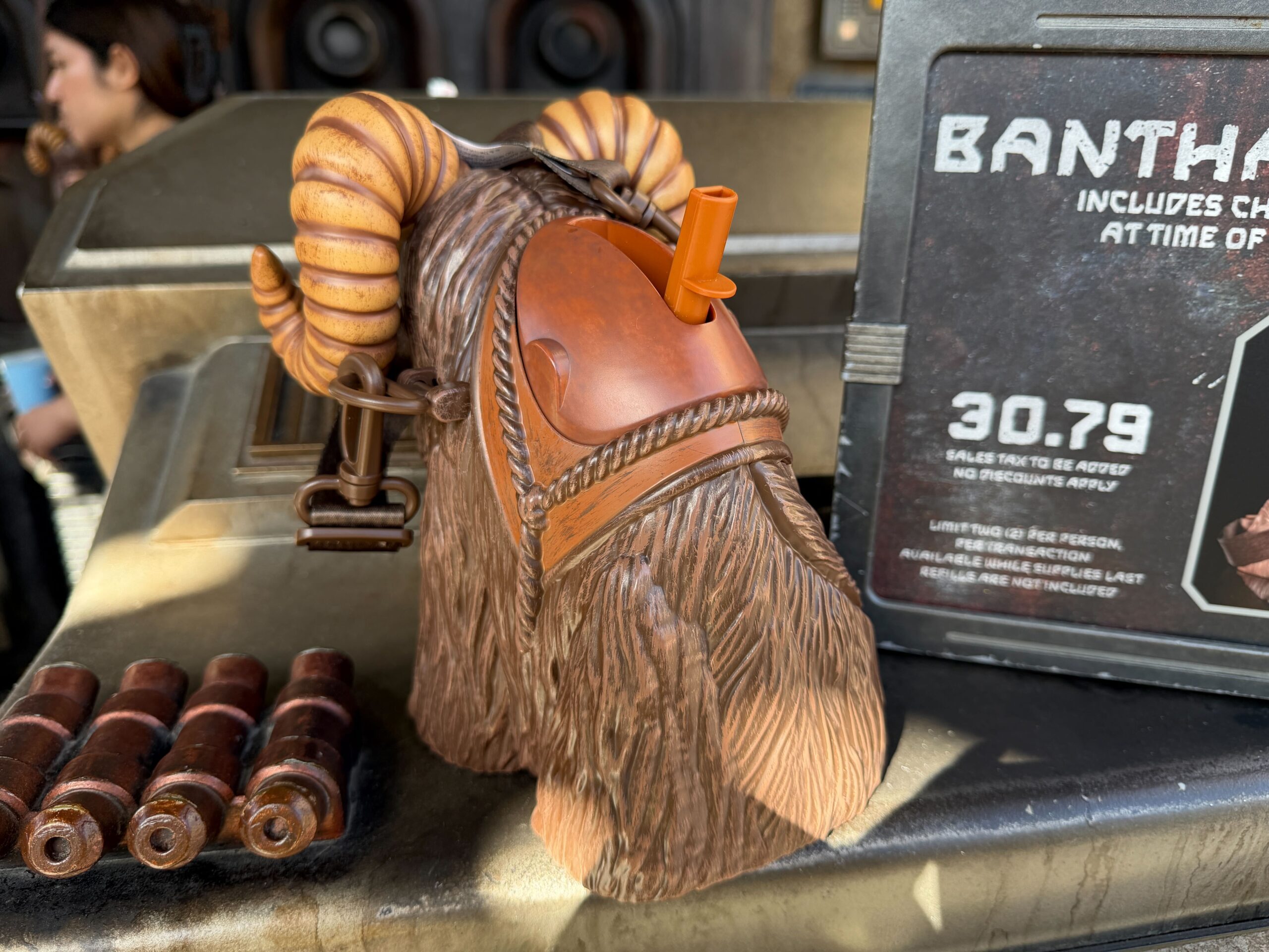 The sipper, which has a brown lanyard, is shaped like a hairy Bantha. These desert-dwellers hail from Tatooine and are largely associated with the blue milk they produce. The front of the sipper shows a shaggy Bantha, and the back has the sipper spout that comes out from the beast's saddle.
