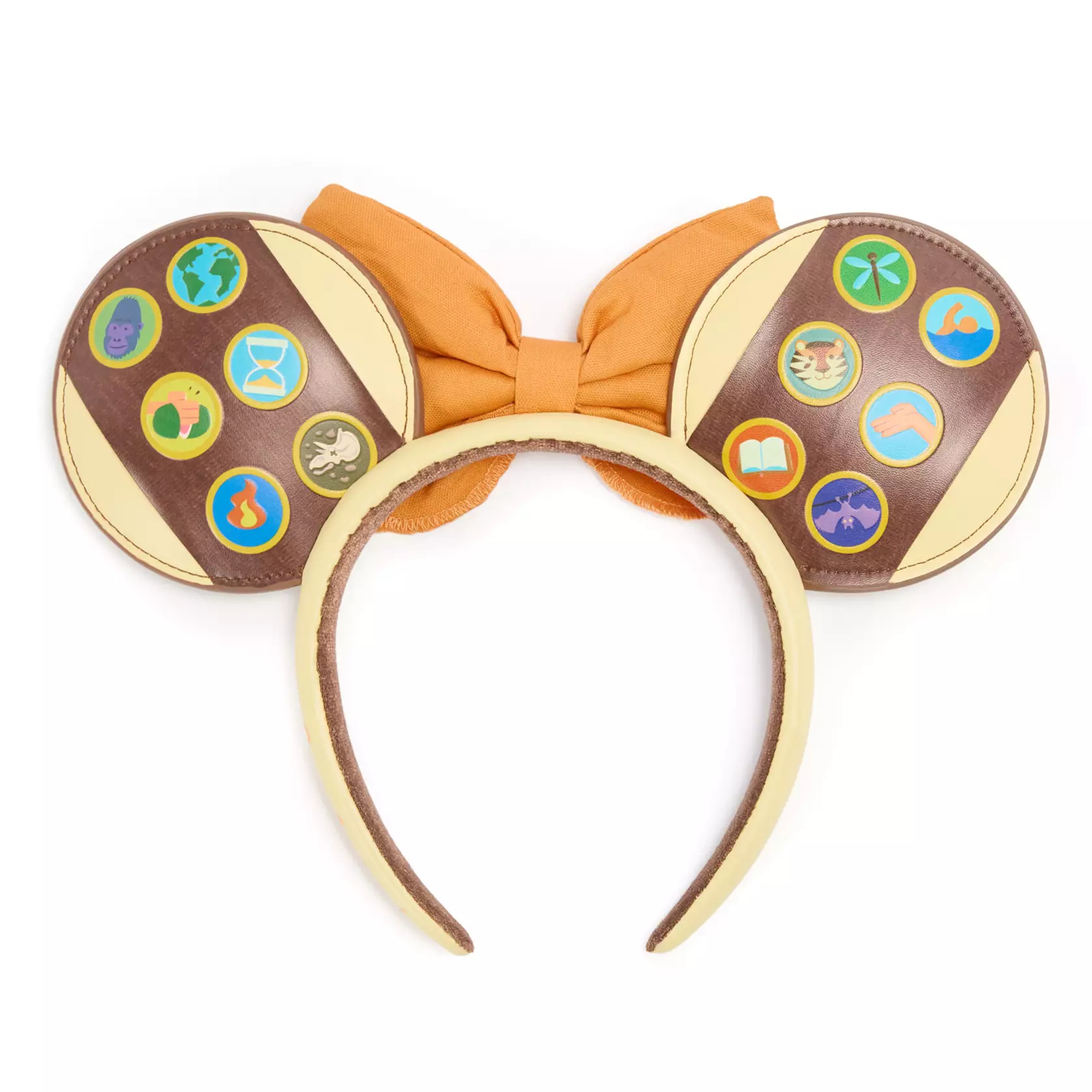 More badges are on the backs of the ears — a gorilla, globe, hand chopping a watermelon, hourglass, campfire, dinosaur bones, dragonfly, swimming, tiger, open palm, book, and bat. “Explore!” is on one side of the headband, which is lined with blue velour.