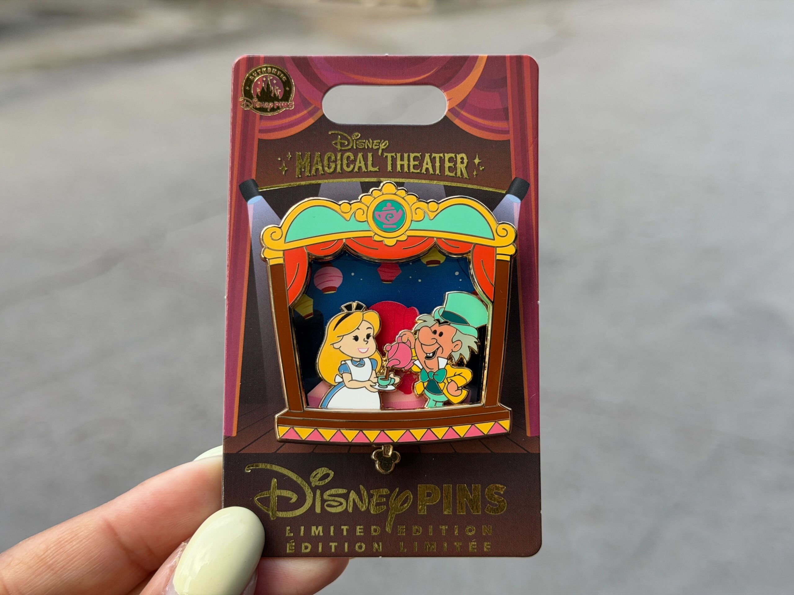 The fourth installment of the monthly Magical Theater pins centers on Alice in Wonderland. Seen on the stage are Alice and the Mad Hatter. Mad Hatter is pouring Alice a cup of tea. In the background is the tea party.