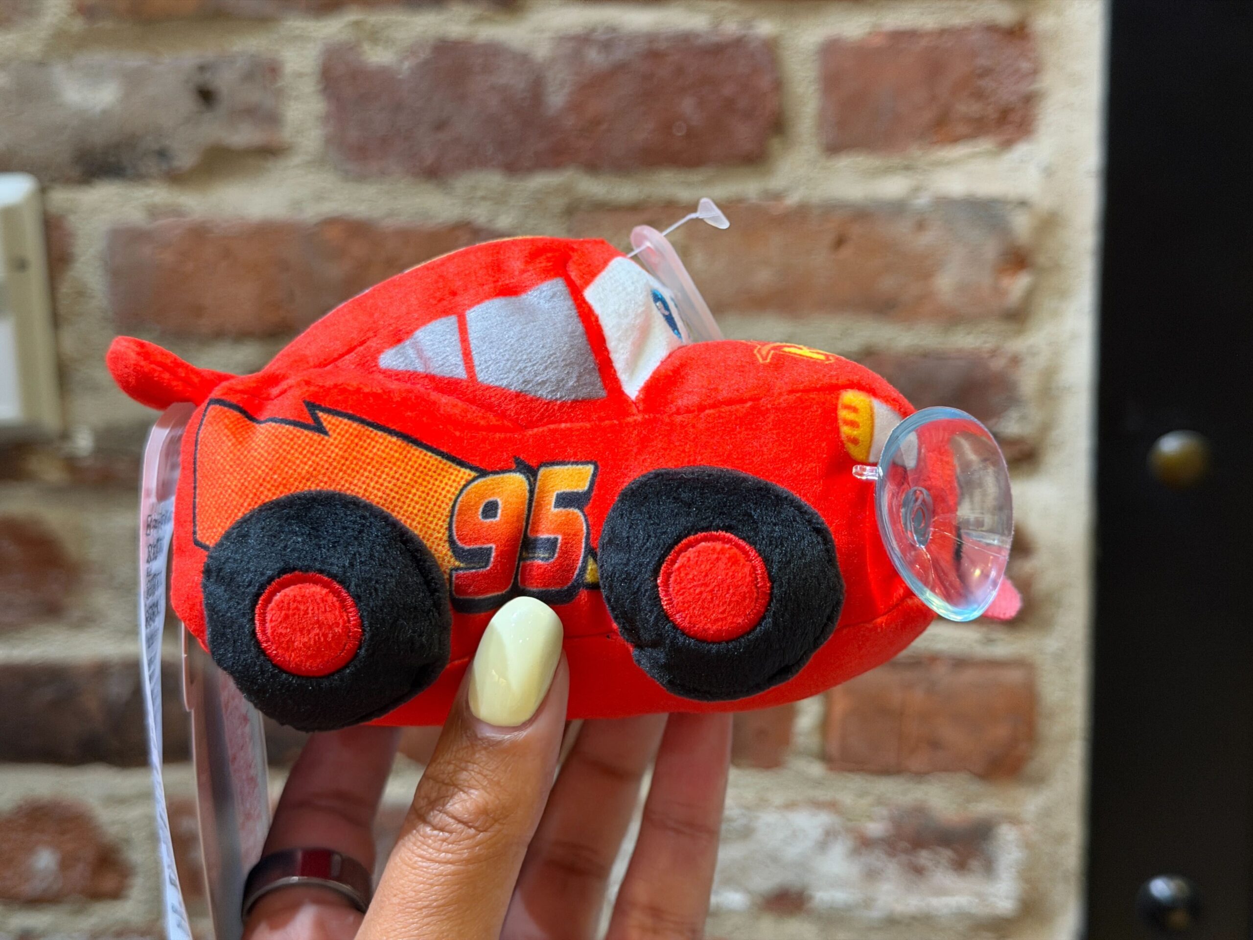 This Lightning plush clings to glass like a car window with two suction cups. Lightning is depicted with his tongue out like he's exhausted from racing.