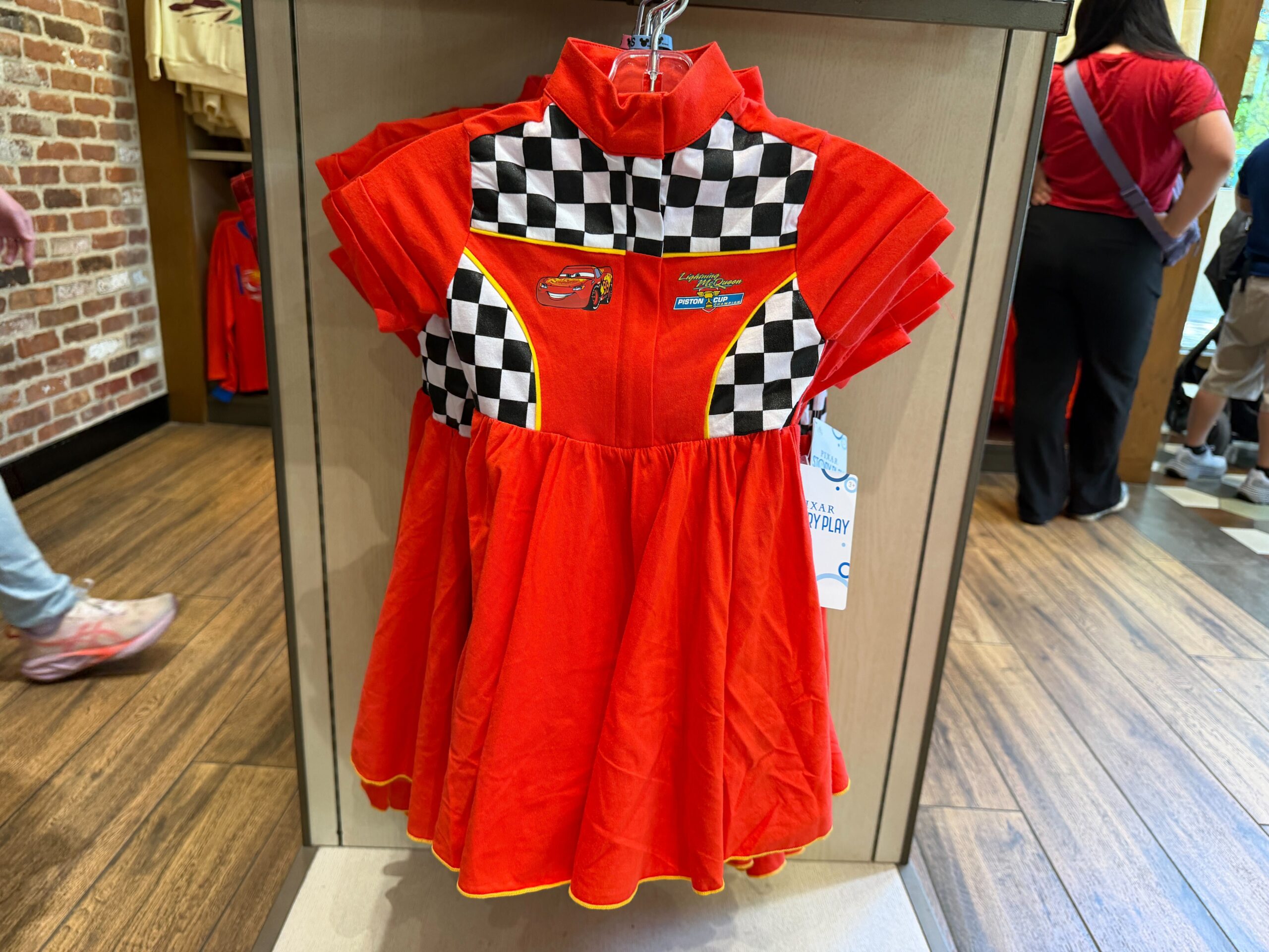 This red dress is decorated with a checkered pattern on the yoke and sides. There's yellow piping along the check and skirt hem.