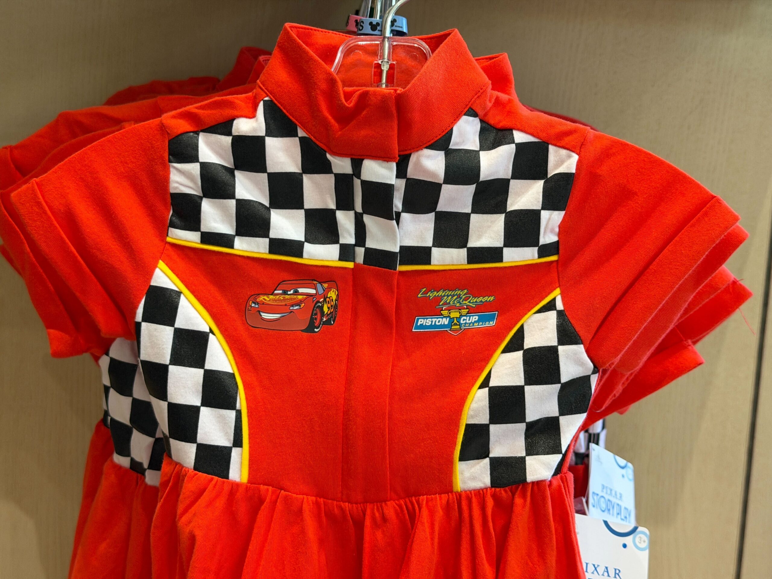 This red dress is decorated with a checkered pattern on the yoke and sides. There's yellow piping along the check and skirt hem.