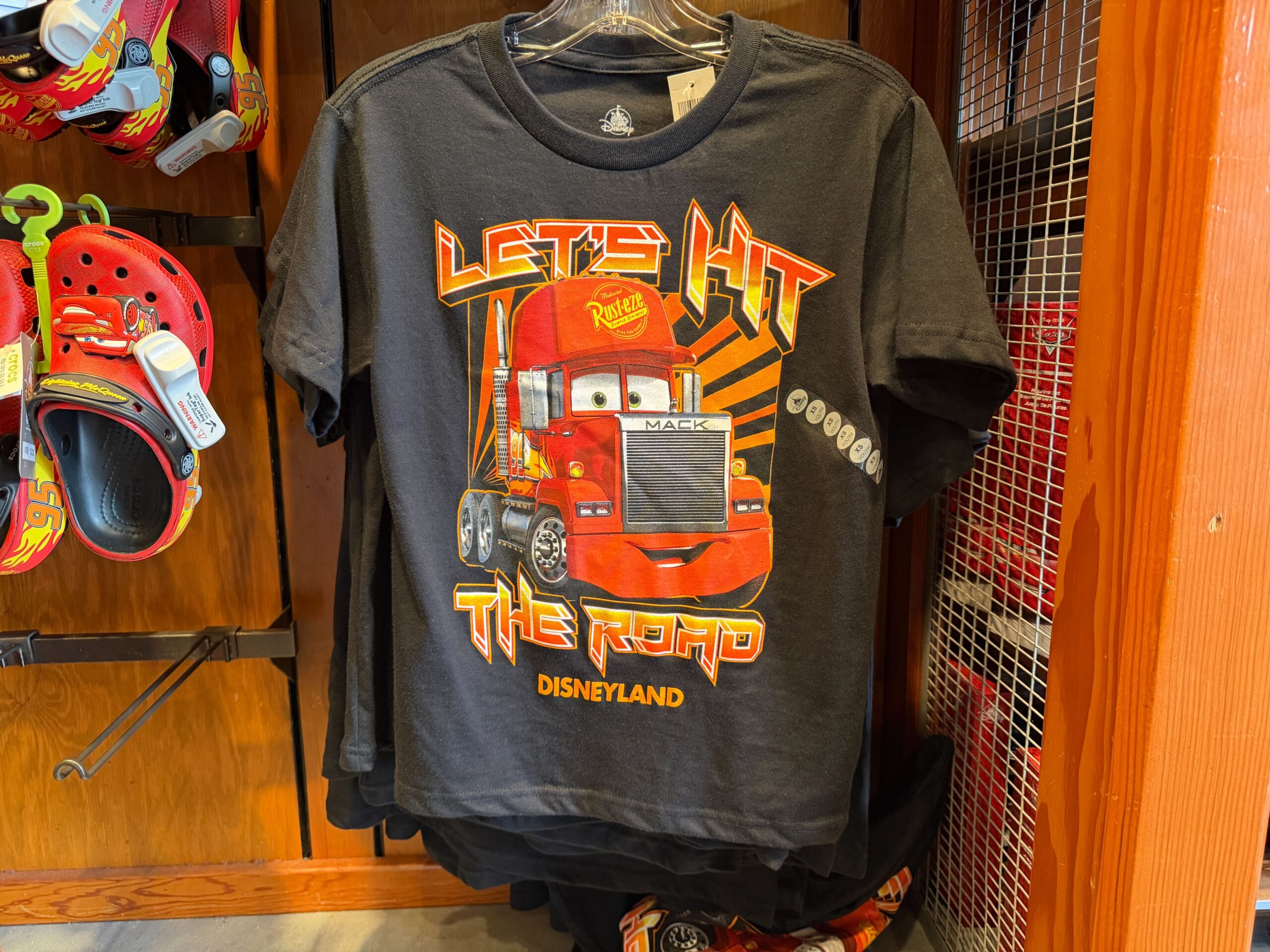 Lightning's friend Mack is on this black tee with red-orange text reading "Let's hit the road." The Disneyland wordmark is in orange at the bottom.