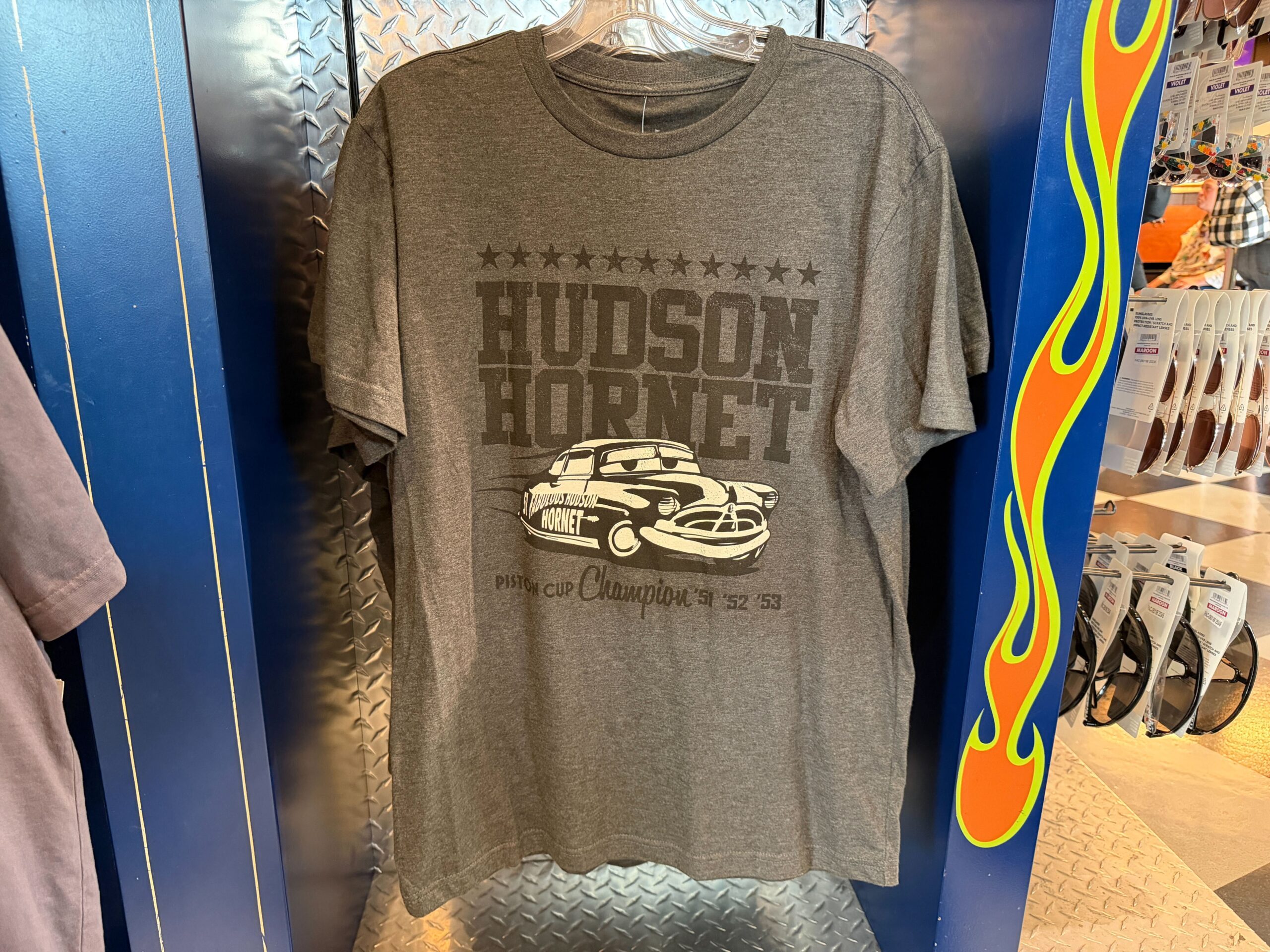 Inspired by the Hudson Hornet a.k.a. Doc Hudson, the famous racecar is pictured in black and white on this heather gray tee. "Hudson Hornet" is in big letters above and behind him, along with a row of stars. Below him is "Piston Cup Champion '51 '52 '53."