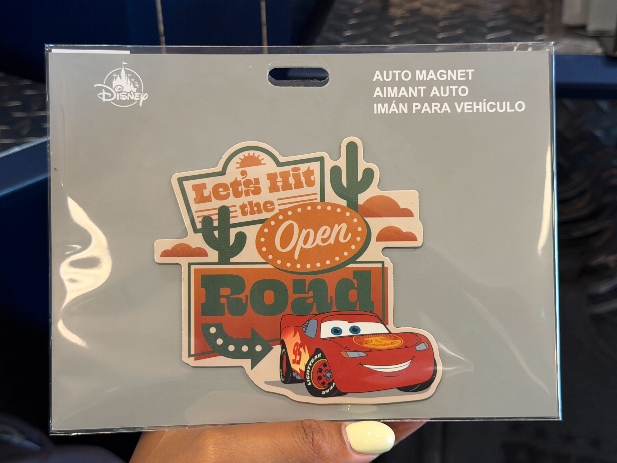 The magnet features Lightning with "Let's Hit the Open Road" on road signs. There are cacti and orange clouds.
