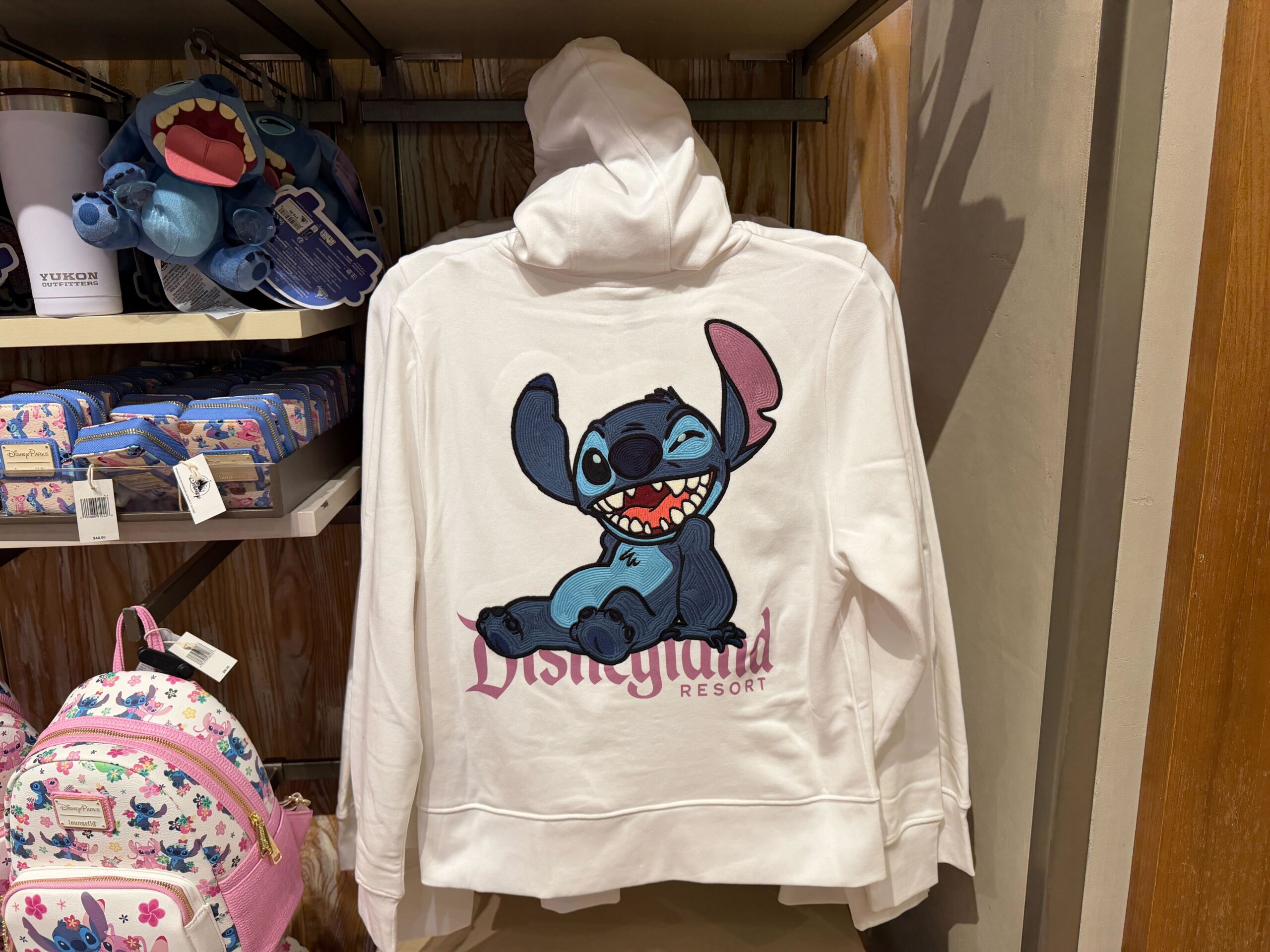 The back of the hoodie has a large design of Stitch grinning while sitting atop a pink Walt Disneyland logo.