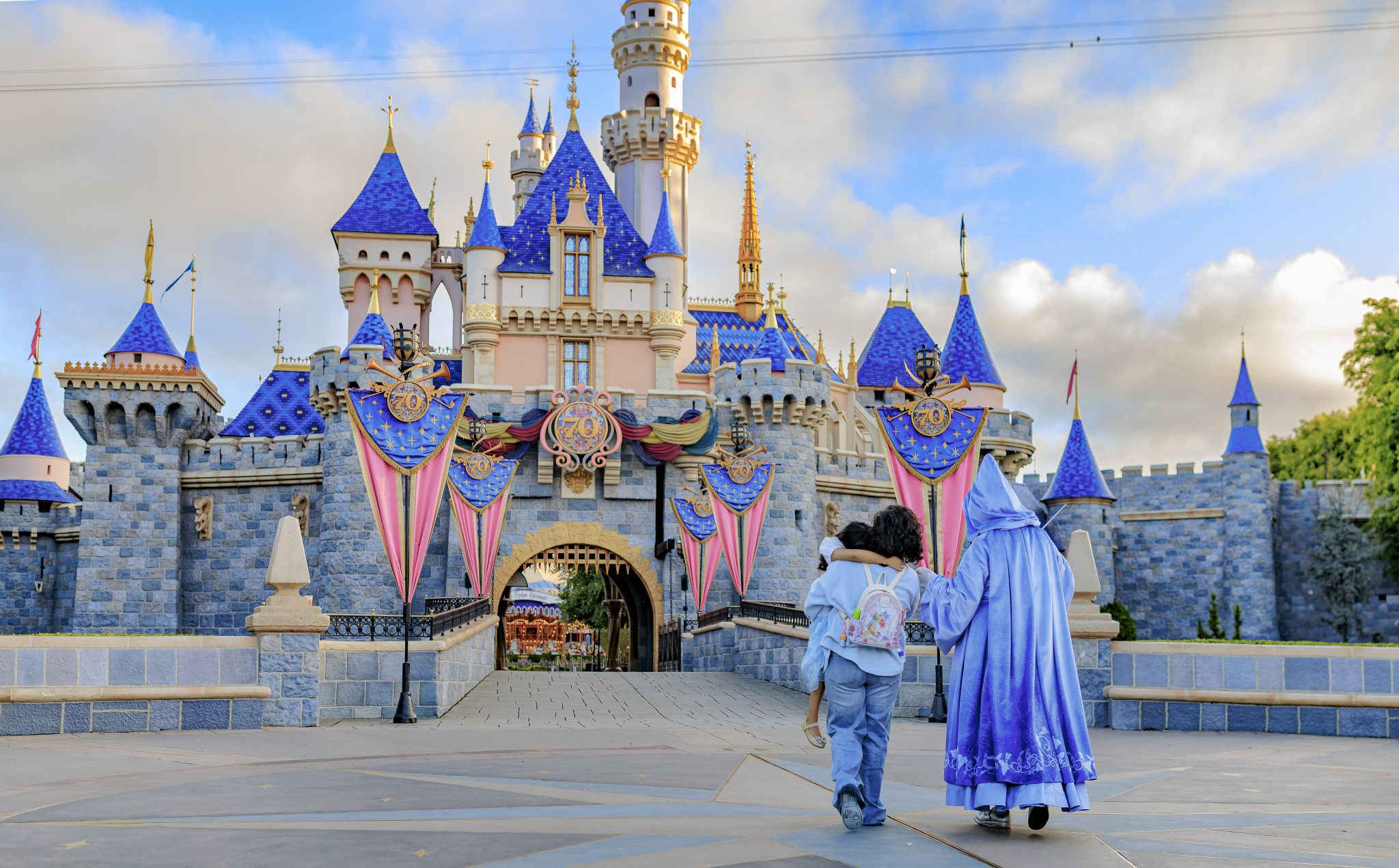 Lilo's family walking with Fairy Godmother in front of Sleeping Beauty Castle.