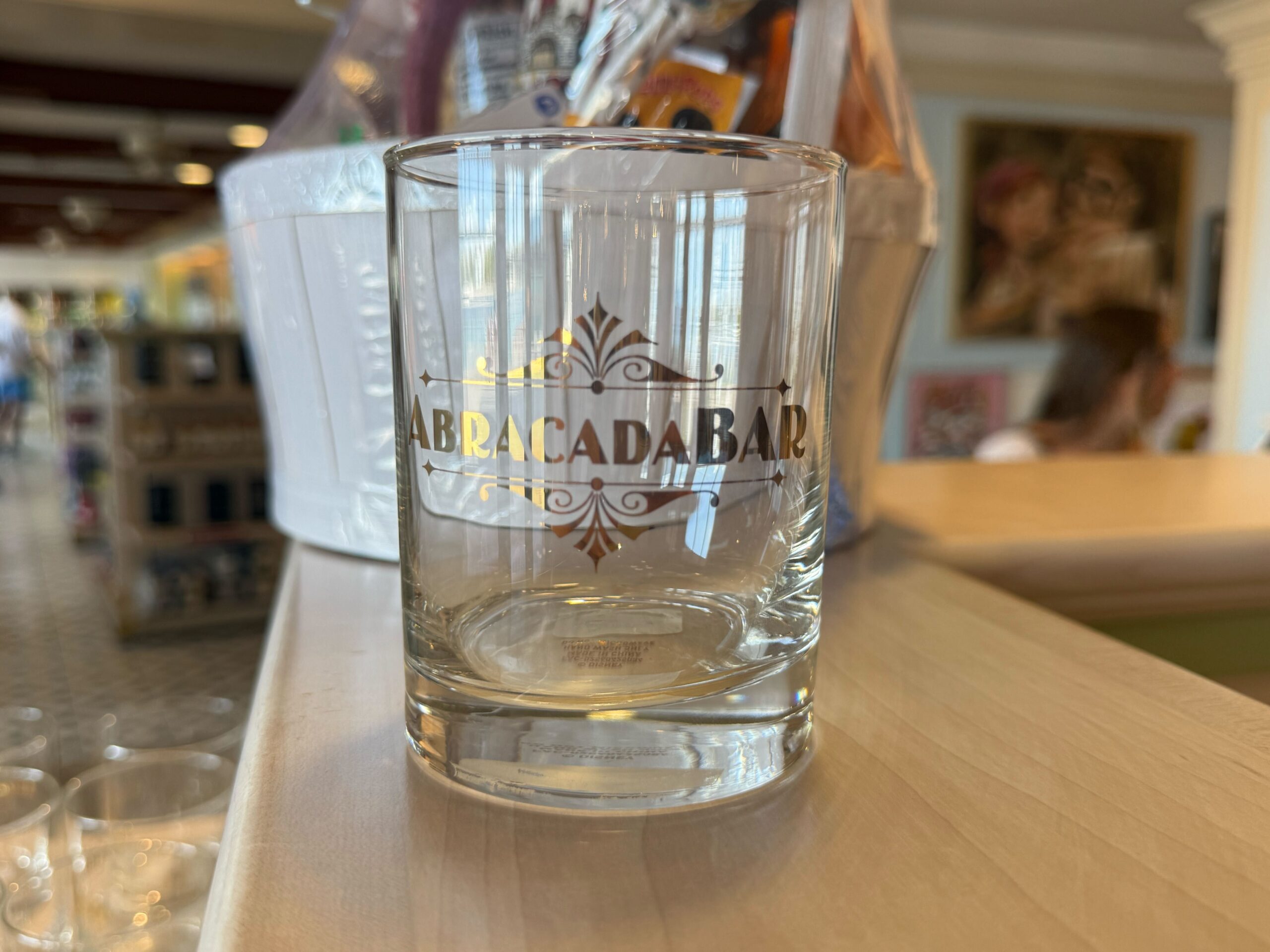 This shot glass features a simple wordmark of the Abracadabar with filigree on the top and bottom.