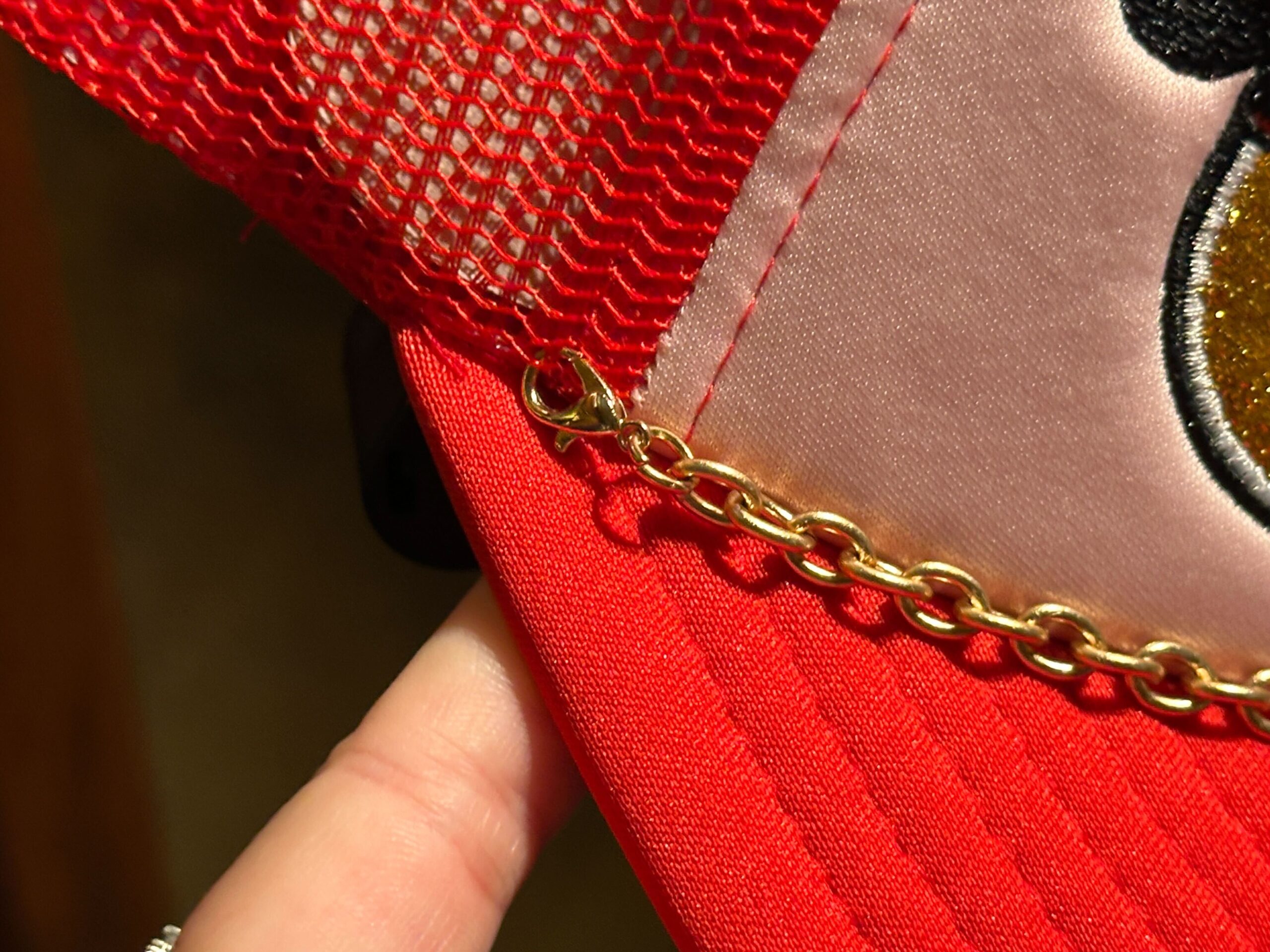 Close-up of chain on the front of the Disney World Icons Red Trucker Hat.