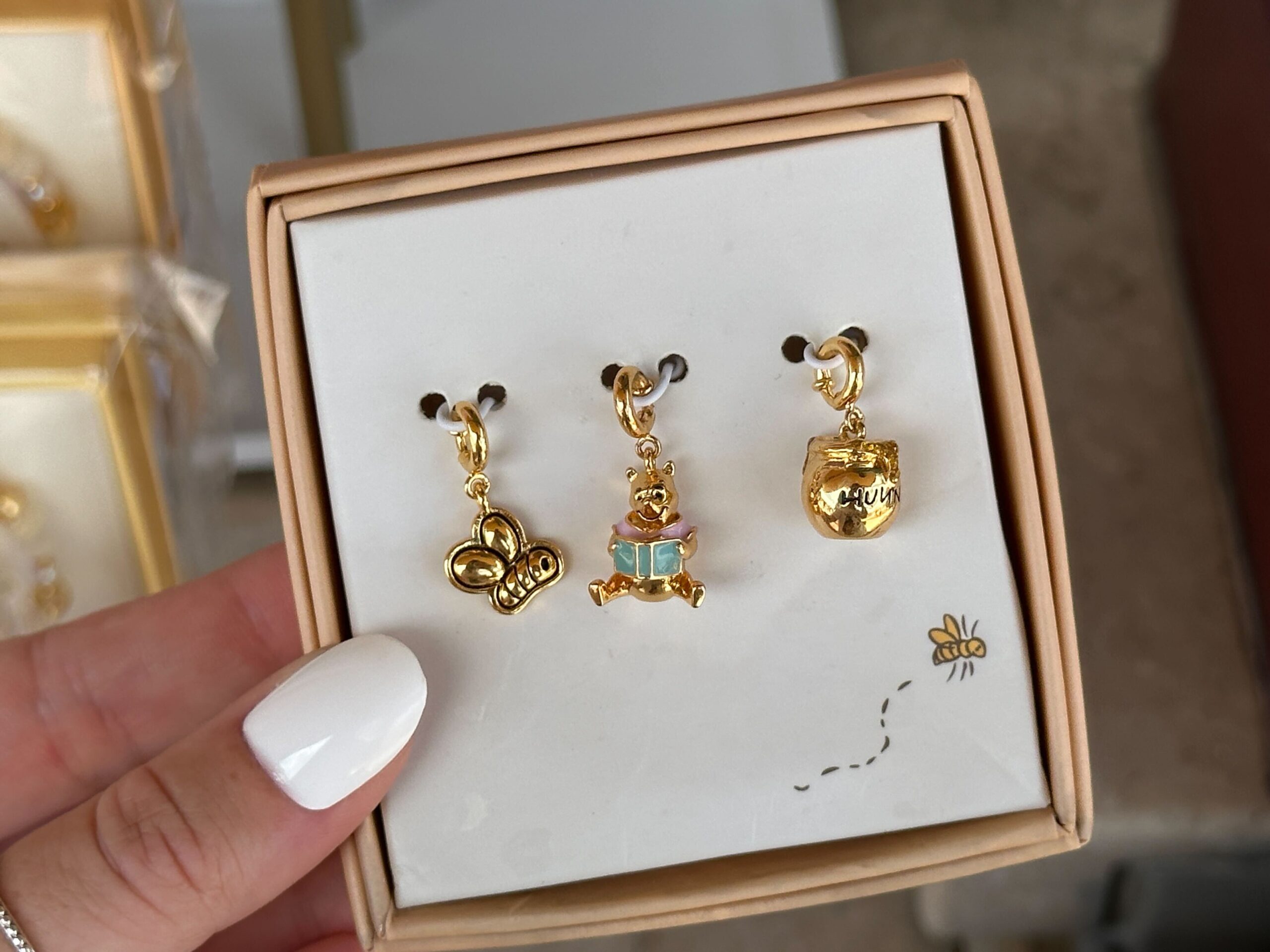 This trio of charms comes “straight from a storybook” and features three icons evocative of Pooh and his fancy-free lifestyle: a charm of Pooh’s pot of “Hunny,” a charm for a cute flying bee, and, of course, a charm of Pooh himself enjoying a book.