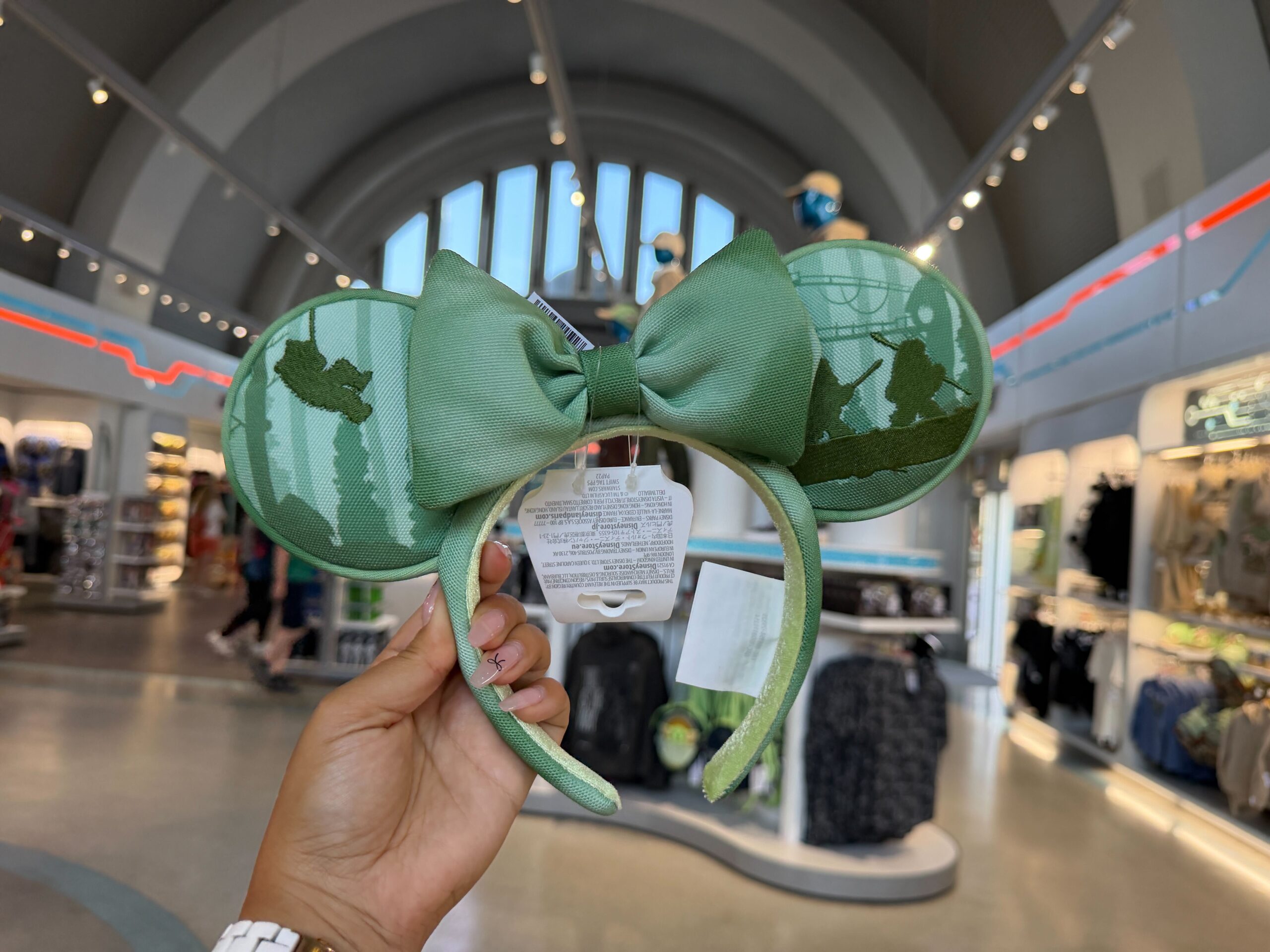 The Endor forest is printed across these ears. Fuzzy Ewok silhouettes are embroidered. The bow is pale green with a slight gradient at the edges. The headband is covered in the same green fabric with lime green velour lining.