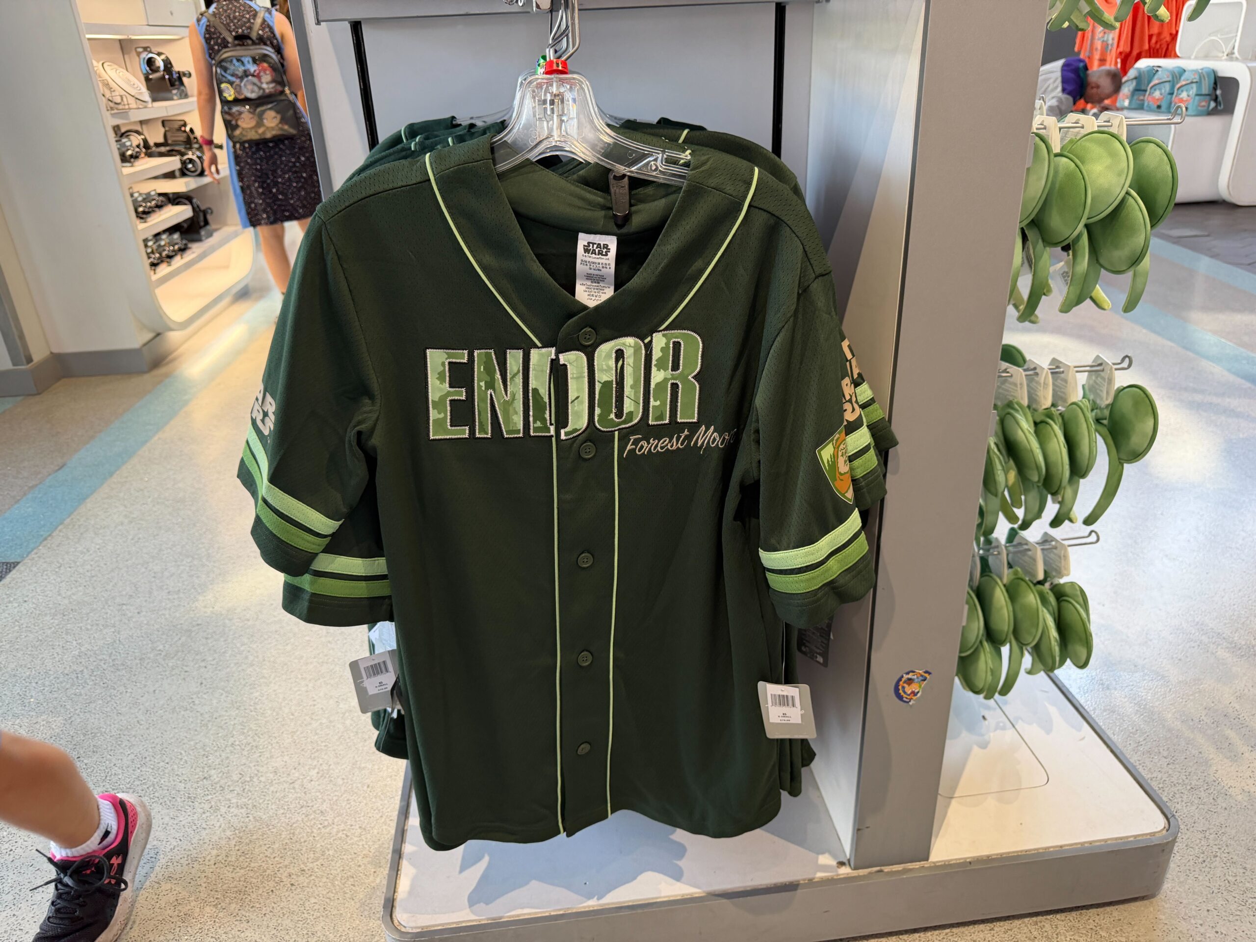 "Endor" is across the chest of this emerald green jersey. The lettering features a forest print with Ewok silhouettes. "Forest Moon" is in embroidered script below. The jersey has bright green trim.