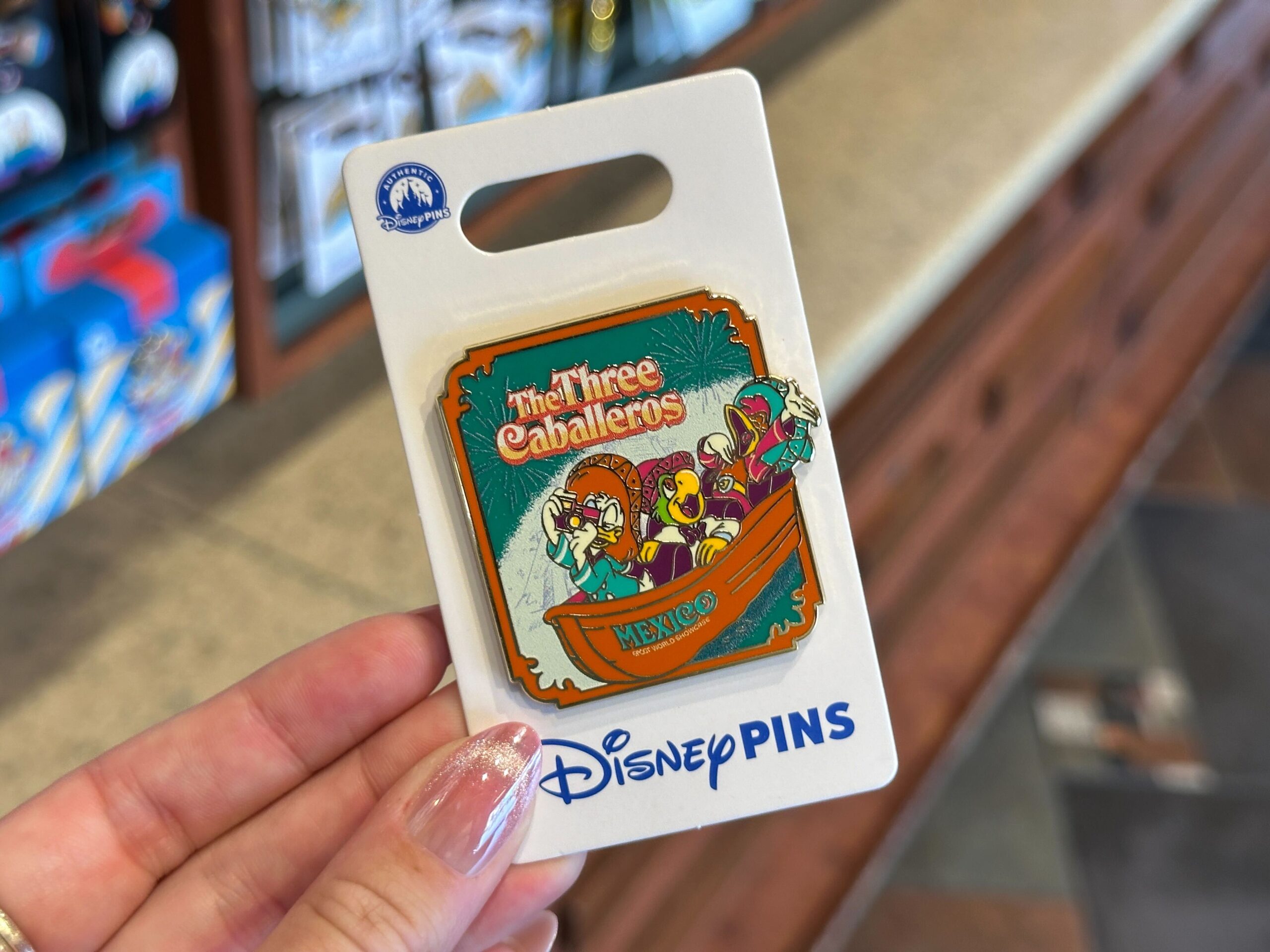 The pin has the three caballeros riding in a boat. The boat has "Mexico EPCOT World Showcase" text on the front.