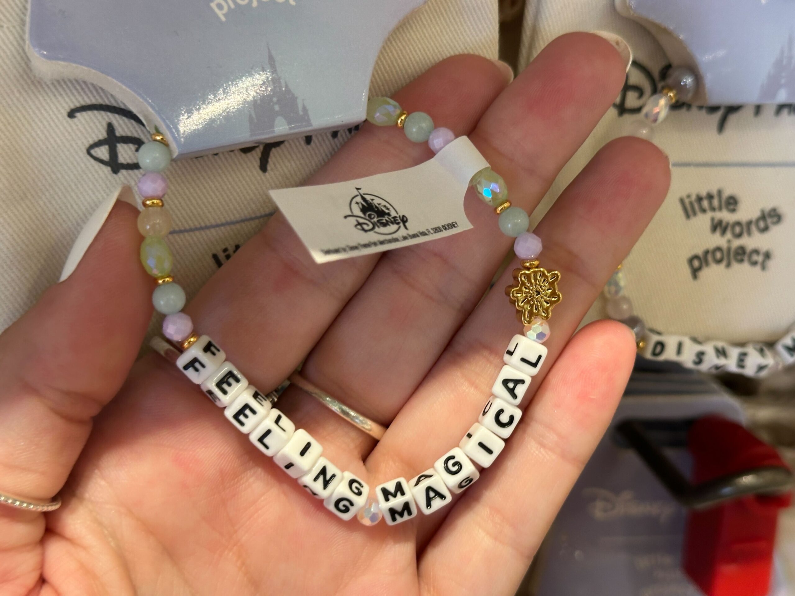 Lastly, the block letters on this bracelet read “Feeling Magical” with a gold firework charm on one end. These beads are in shades of pearlescent, purple, green, blue, and gold.
