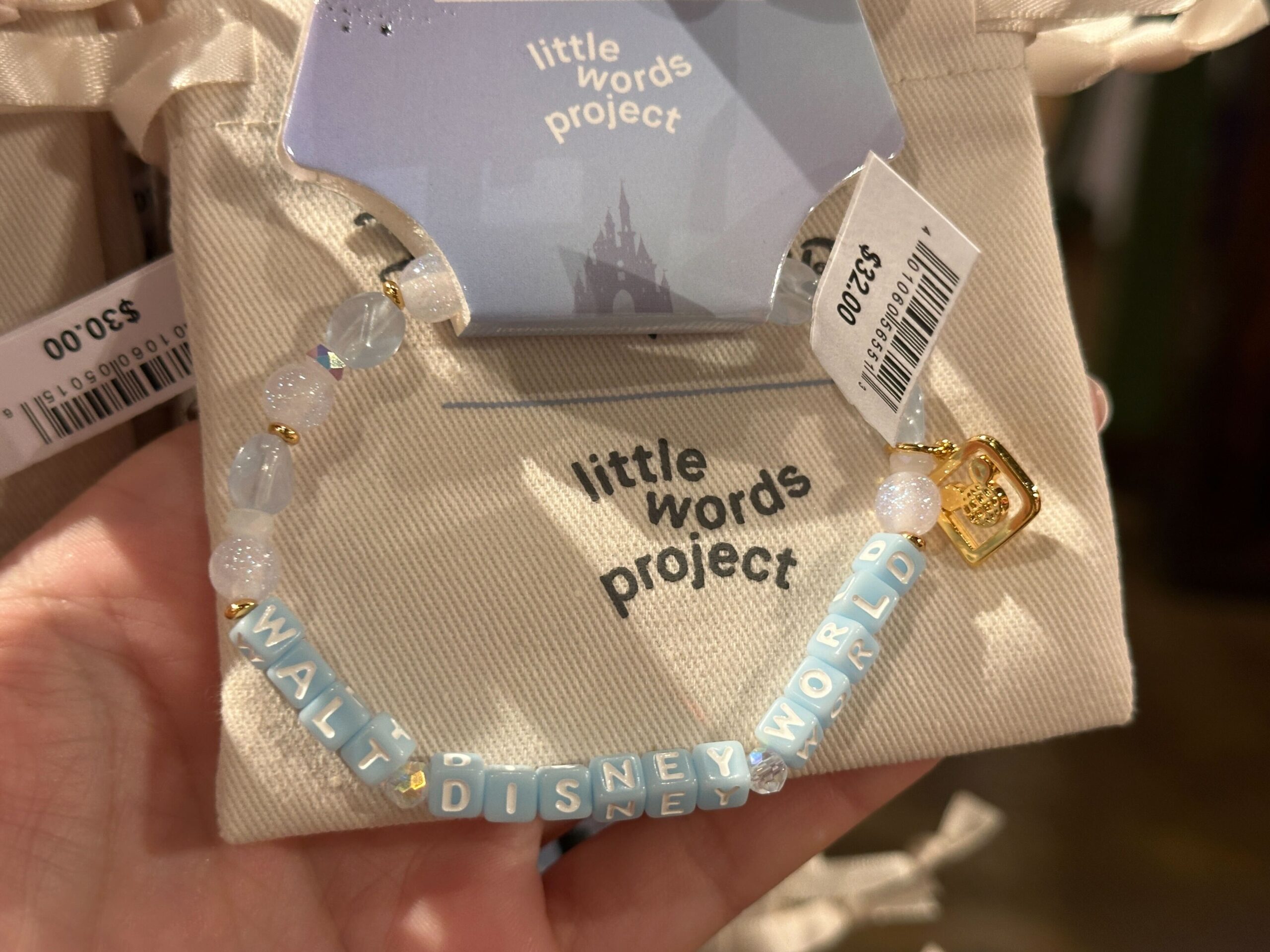 The block letters read “Walt Disney World” with a gold D logo charm on one end. These beads are in shades of light blue, gold, glittery white, and translucent.