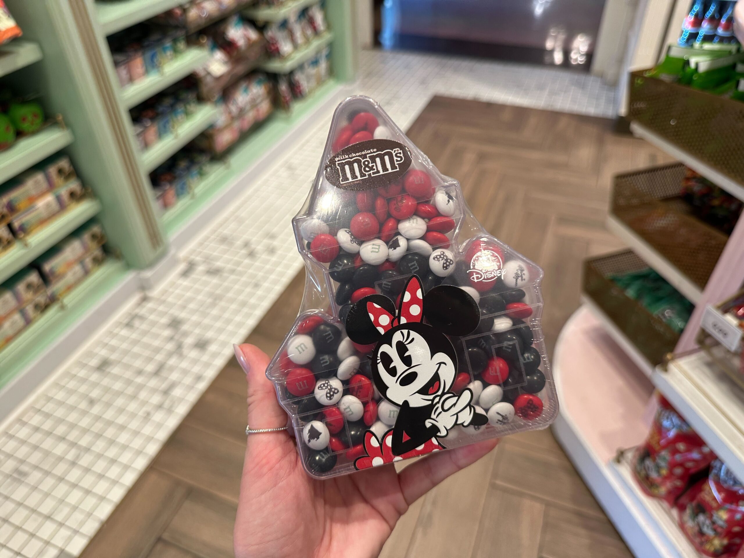 The M&M's candies come in white, red, and black. Images of Cinderella Castle and Minnie bows are stamped on the candies. Minnie is on the front of the travel container. There are approximately 256 pieces of candy in one package.