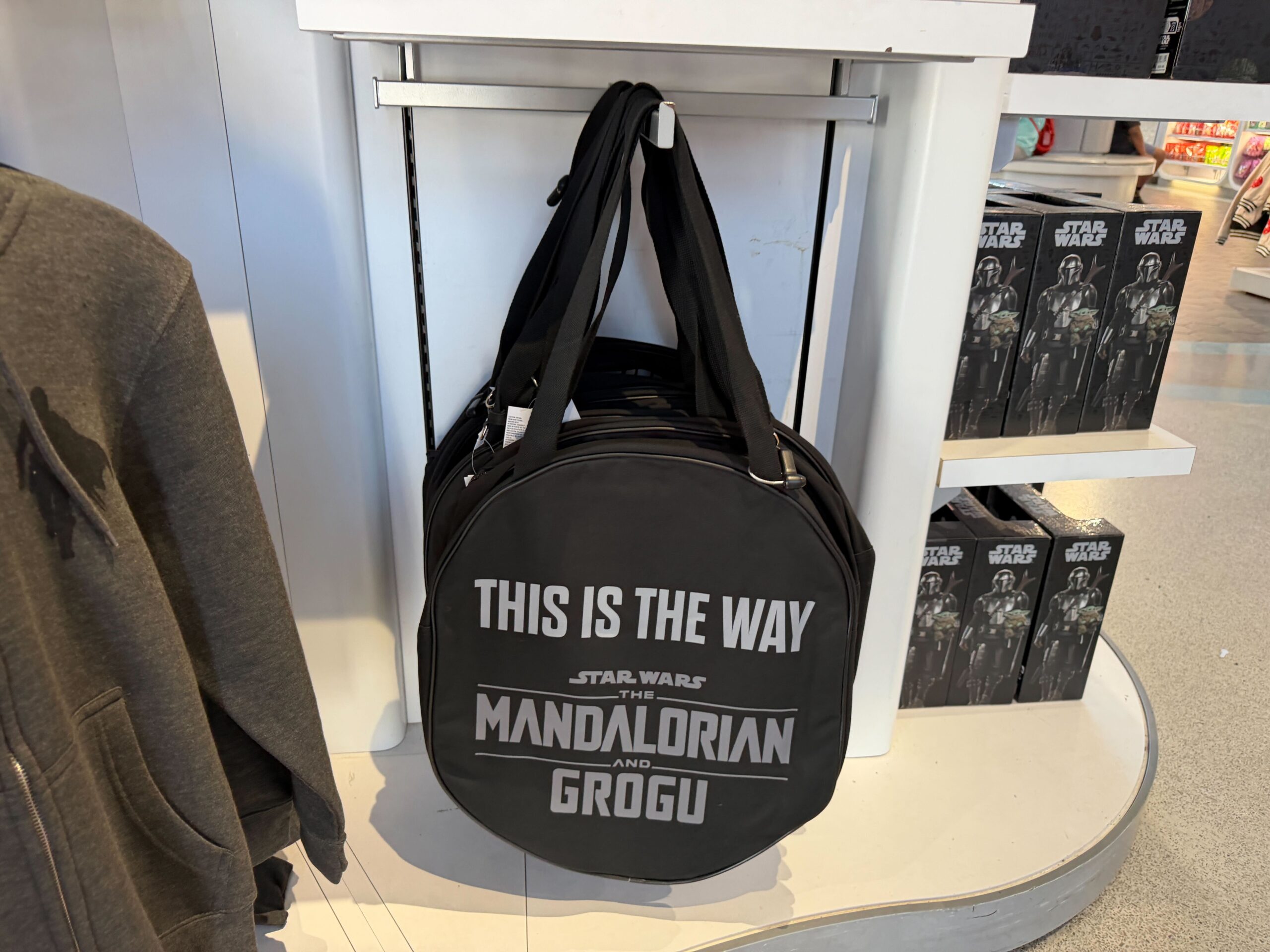 This black canvas tote features a printed image of Mando's silver helmet on the front. On the back is the film's logo and "This is the way."