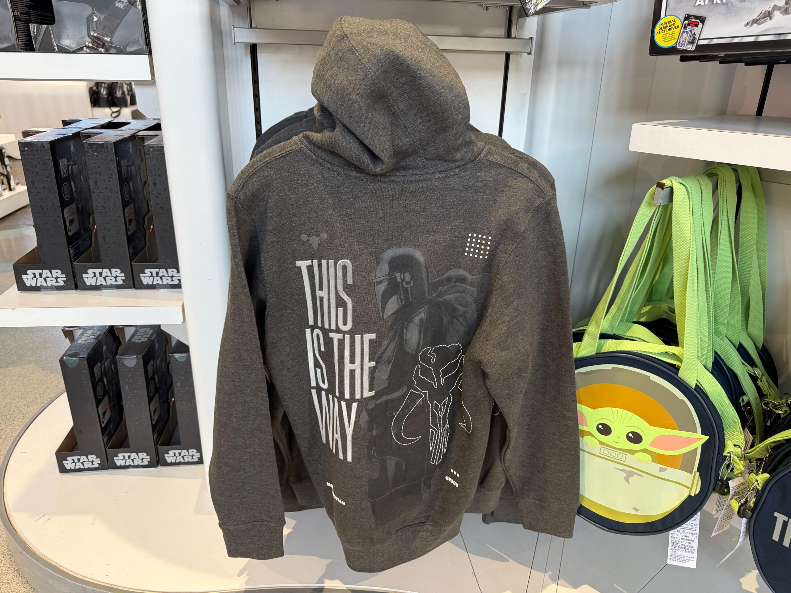 On the back is larger artwork of Mando with Grogu on his back, along with the mythosaur skull emblem. Puffy ink lettering reads "This is the Way."
