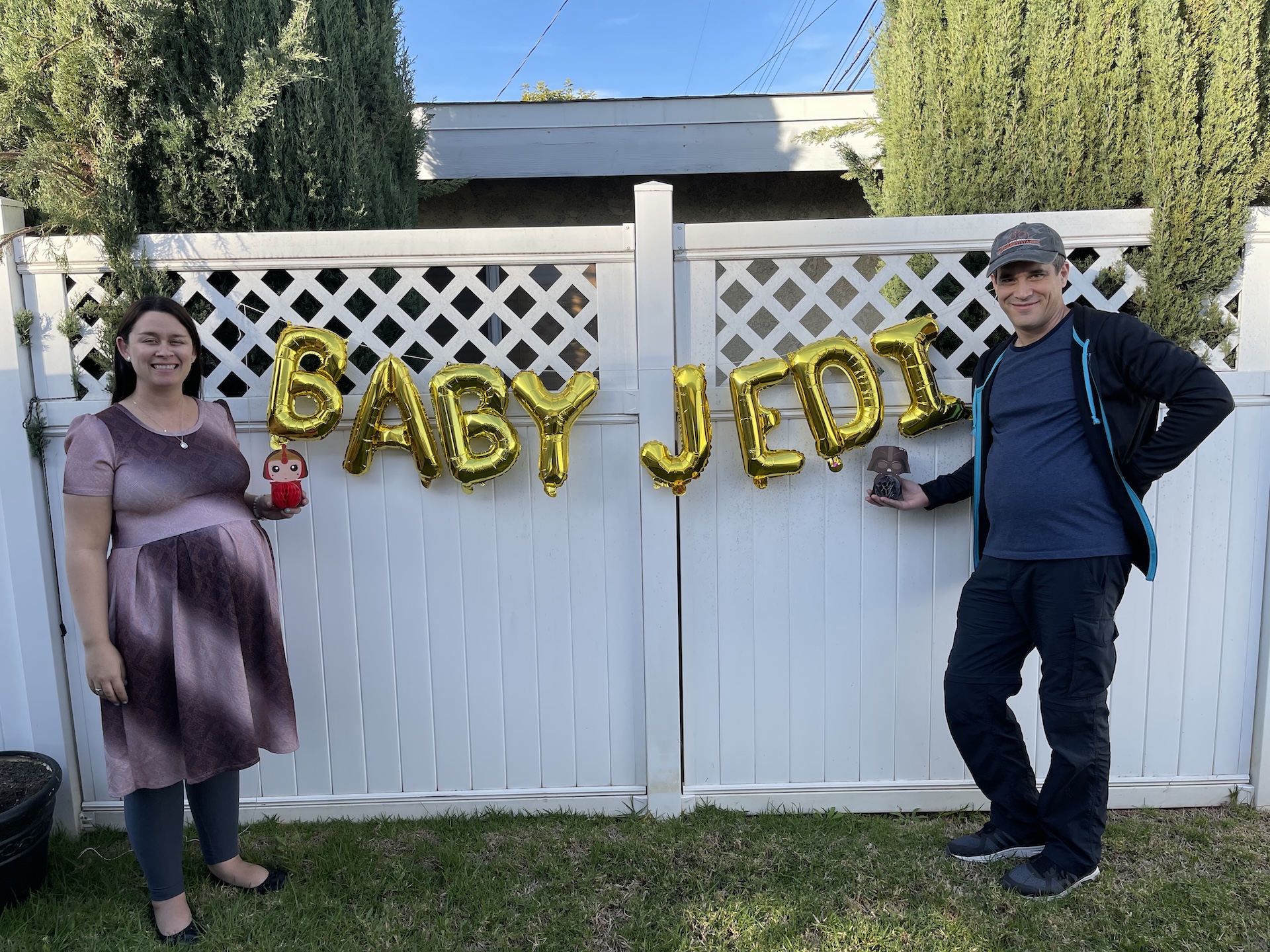 Jennifer and her husband expecting a child with balloon words spelling out "Baby Jedi."