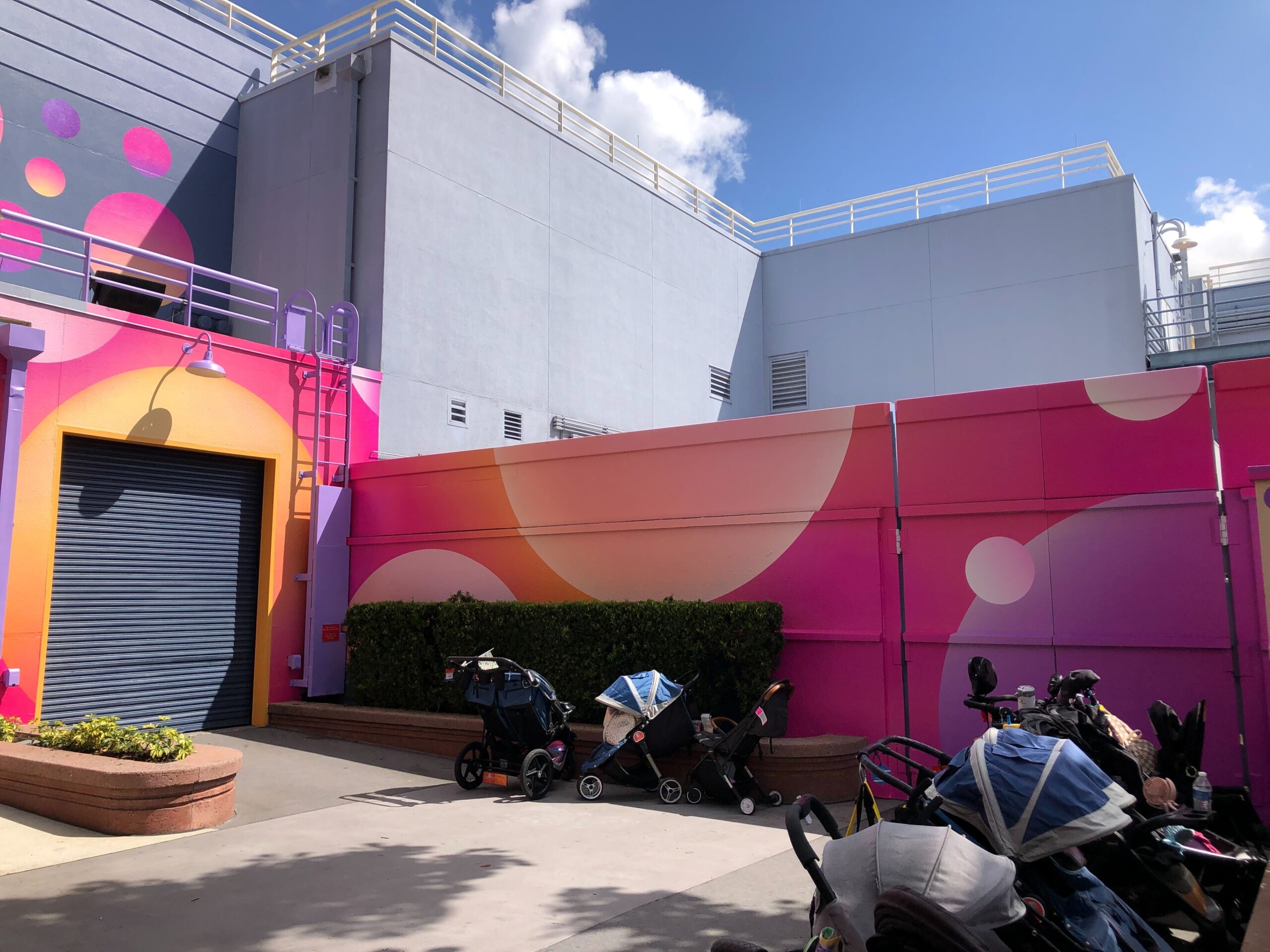 The largest section of the mural is an ombre pink, purple, and orange tone. Bubbles are interspersed in different sizes and colors across the three walls. The longest horizontal section is an ombre background of pink and orange with various bubbles painted on it.
