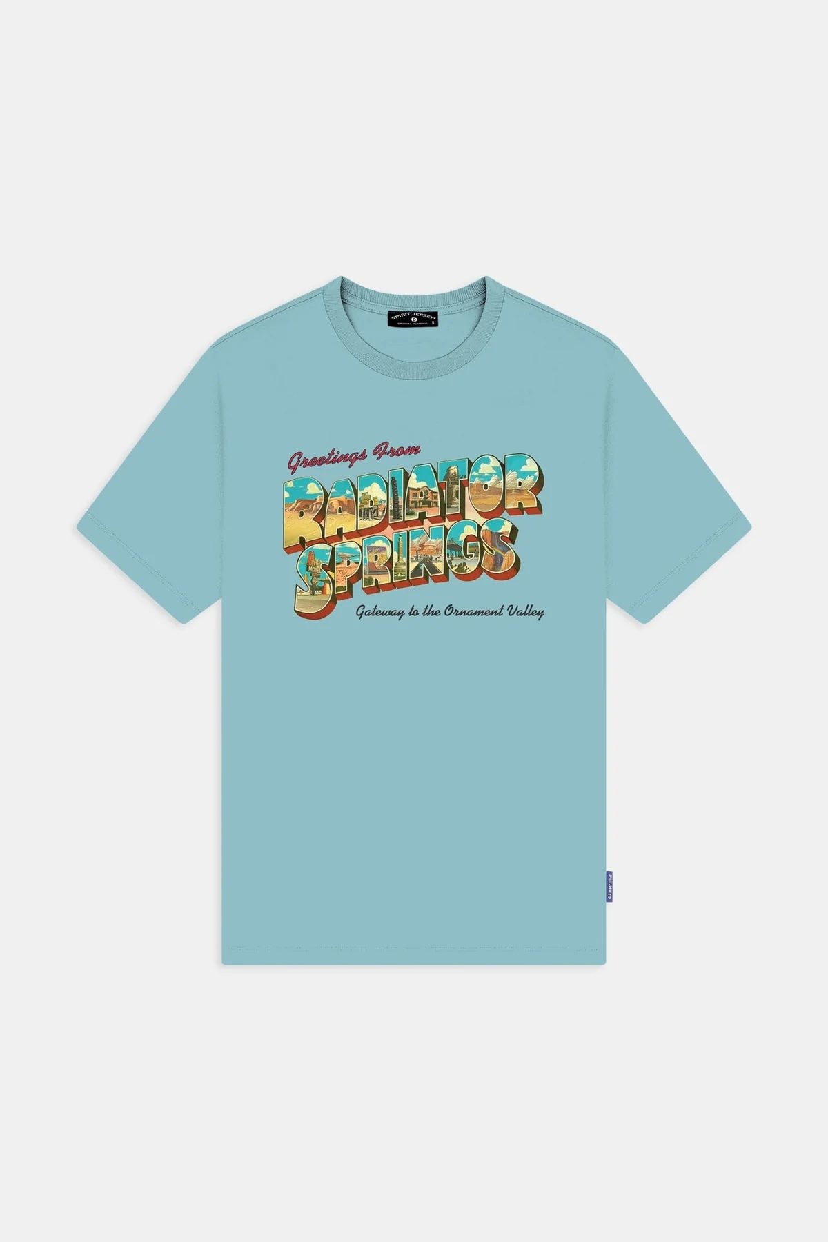 The front of this light blue Radiator Springs shirt is meant to look like text from a postcard. It says "Greetings from Radiator Springs" and "Gateway to the Ornament Valley." The "Radiator Springs" block letters have images of the town itself in them.