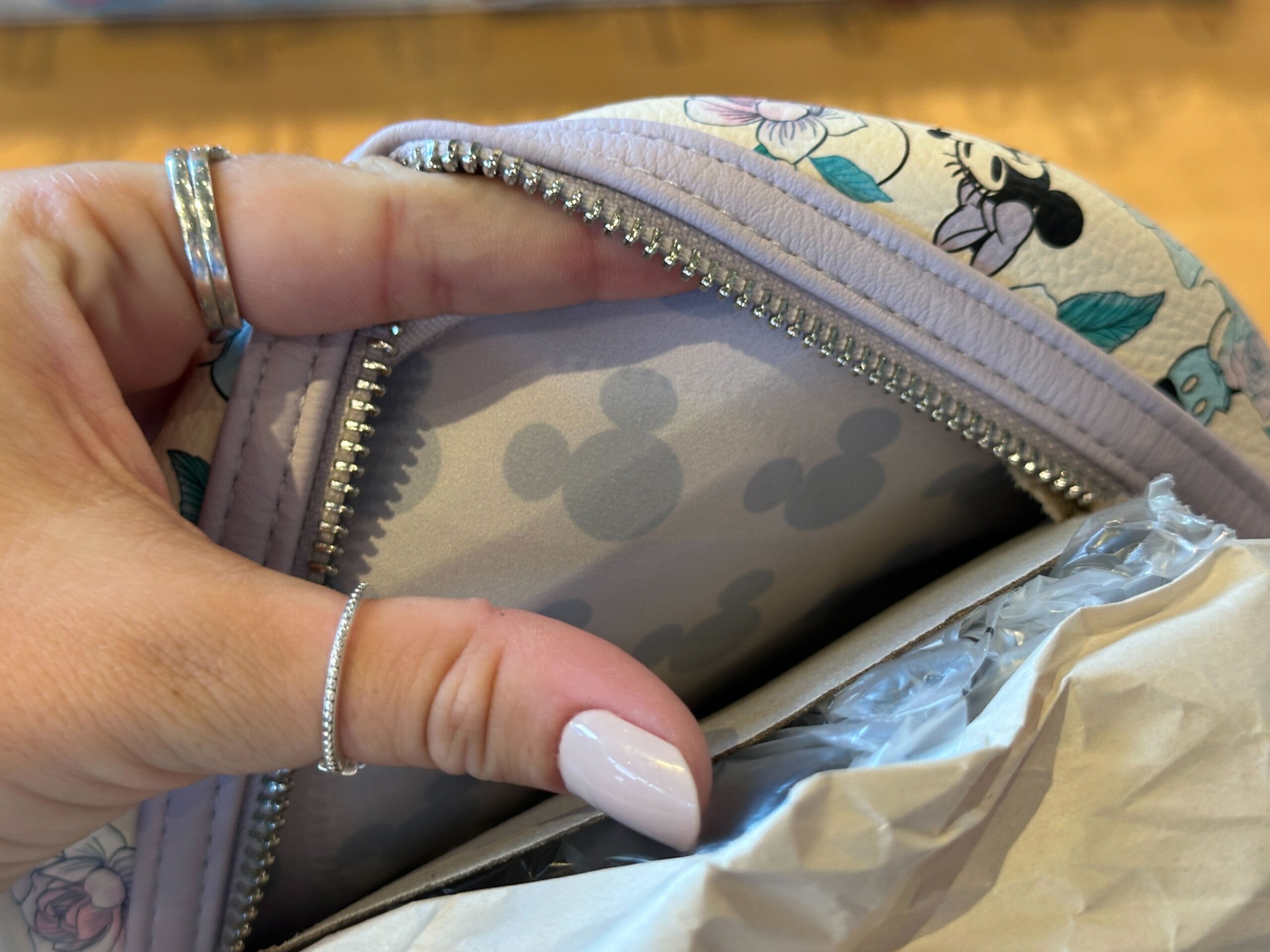 The interior print is periwinkle with all-over Mickey icons. The zipper and hardware are silver.