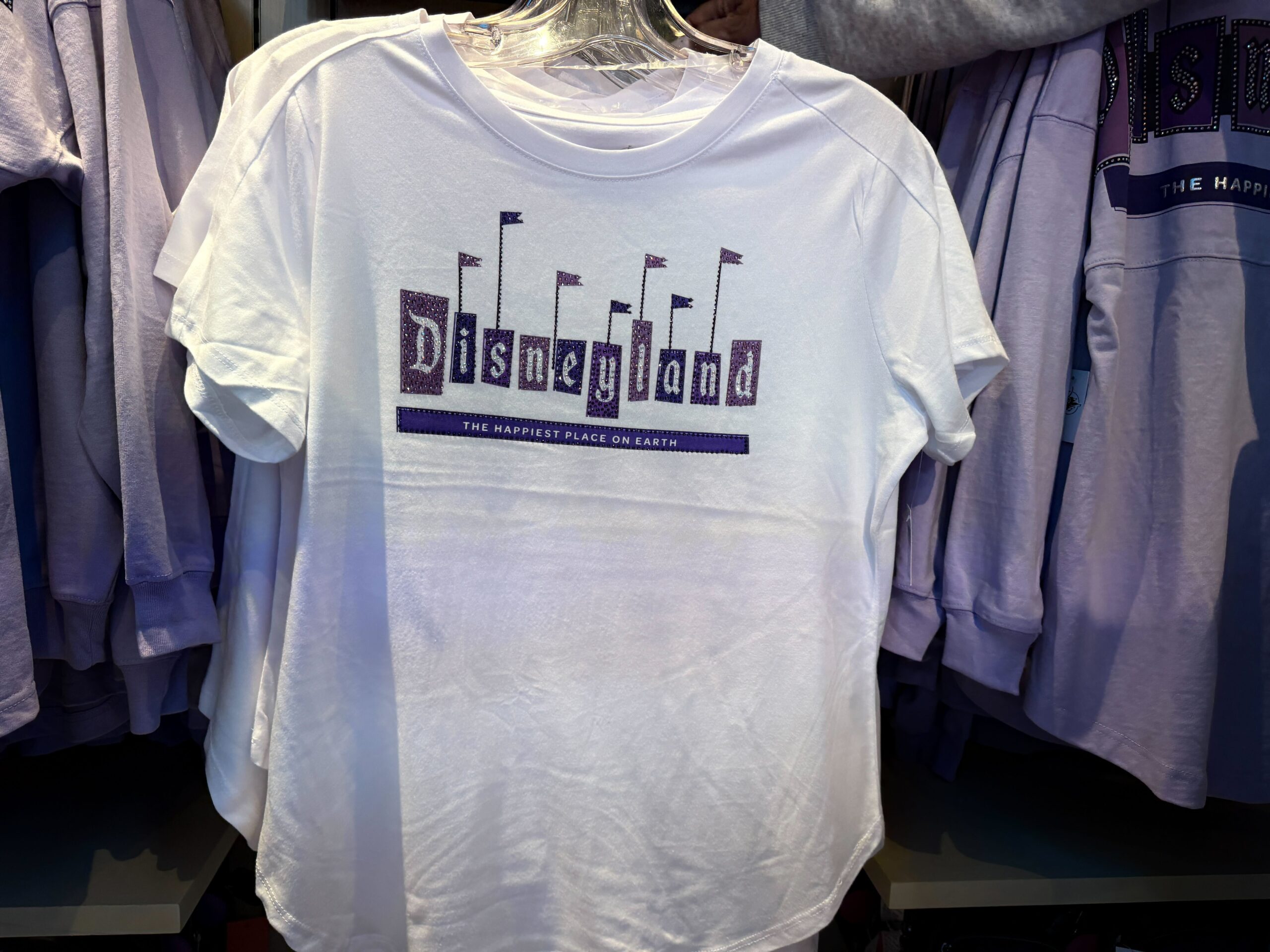 This light purple shirt features the Disneyland 70 logo on the left chest. Silver puffy ink and rhinestone accents highlight the logo.