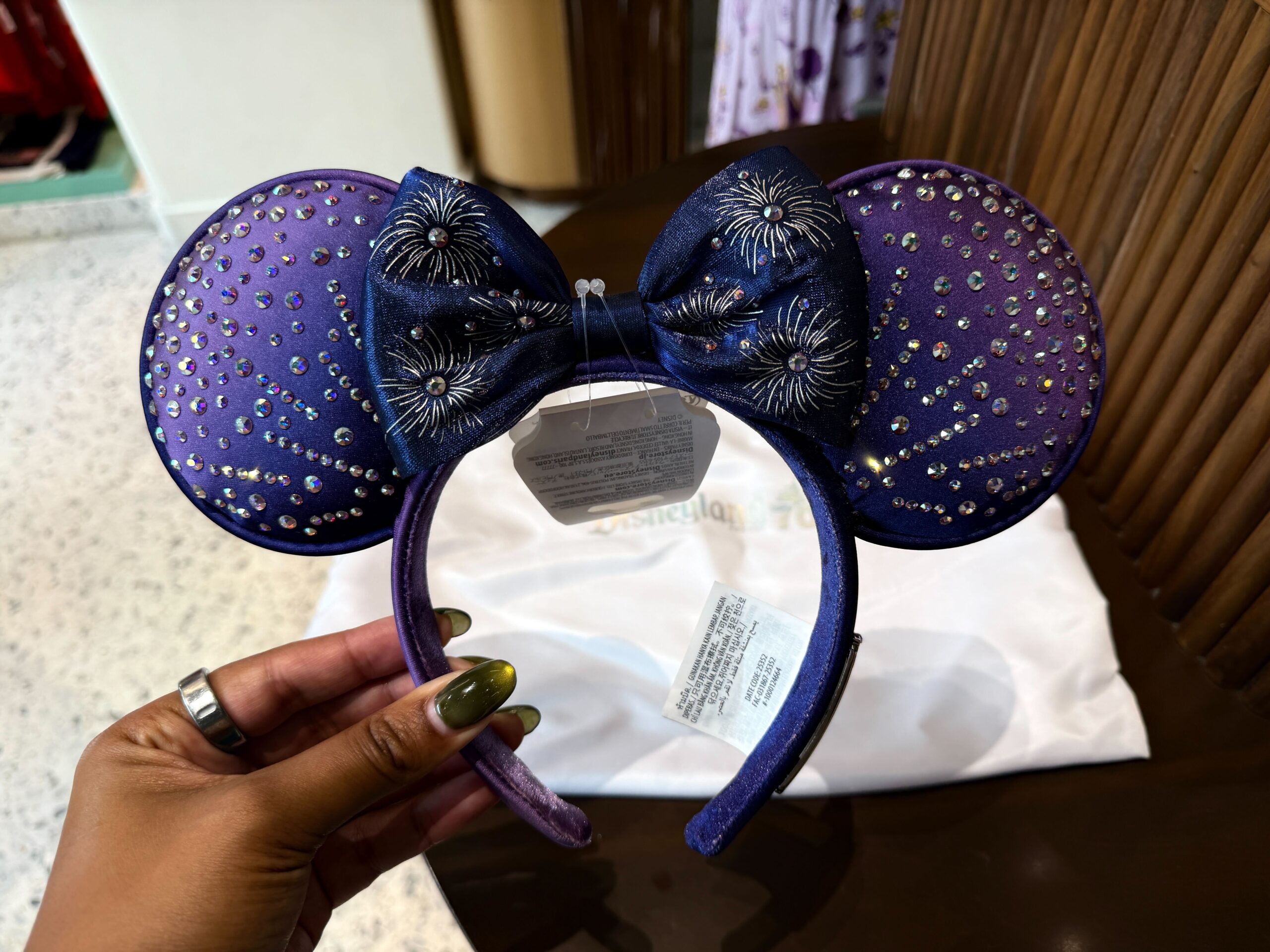 The ear headband has a purple ombré design with the same Swarovski crystal pattern across both sides. It has a velvet bow with a fireworks pattern.
