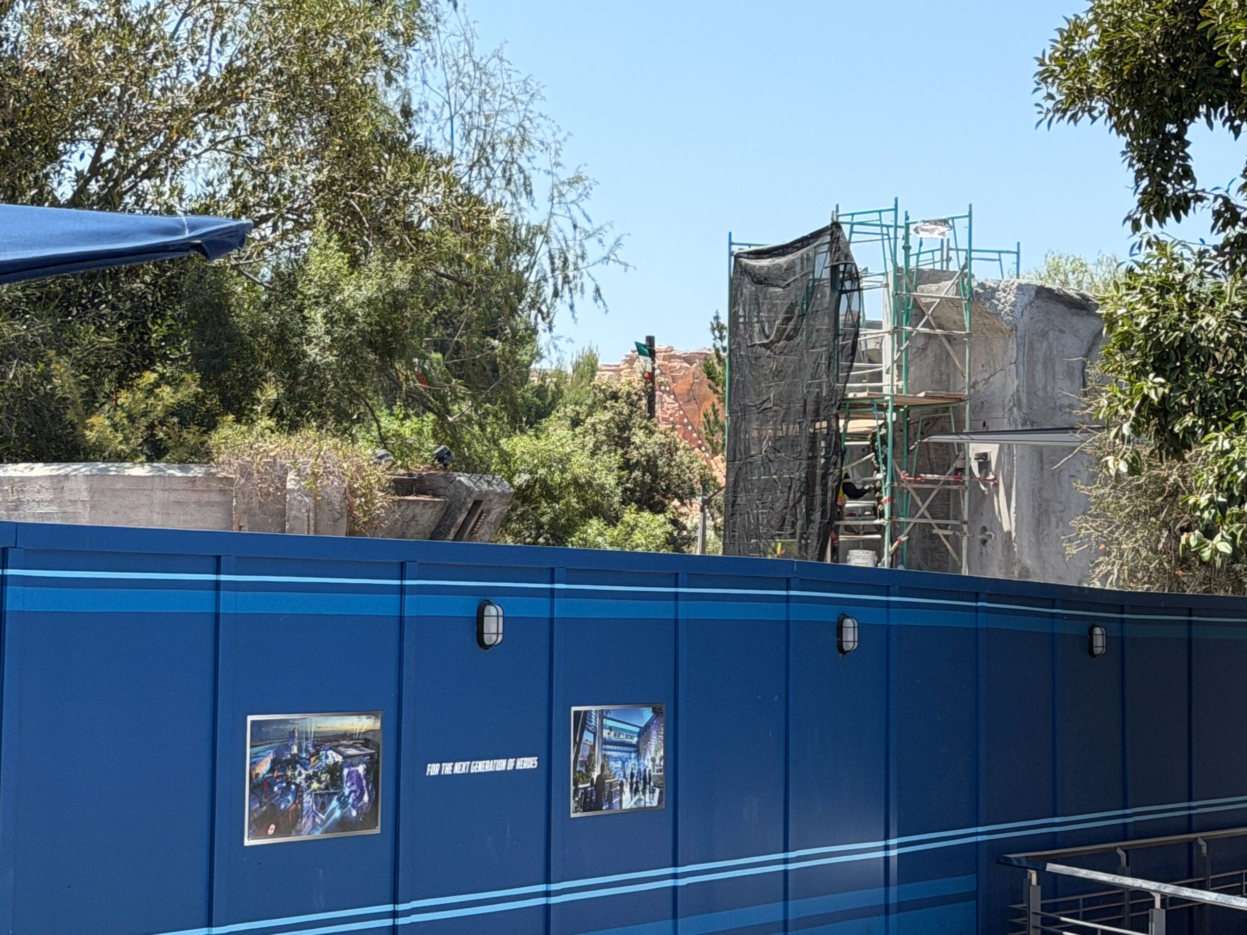 Over by a nearby concrete structure, there is less green scaffolding, but new black scrim.