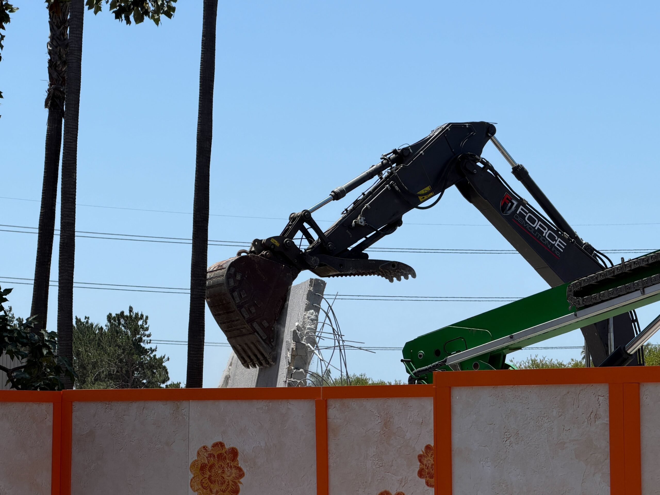 The bucket reached around to the back of the concrete wall and pulled it down, creating a small cloud of dust.