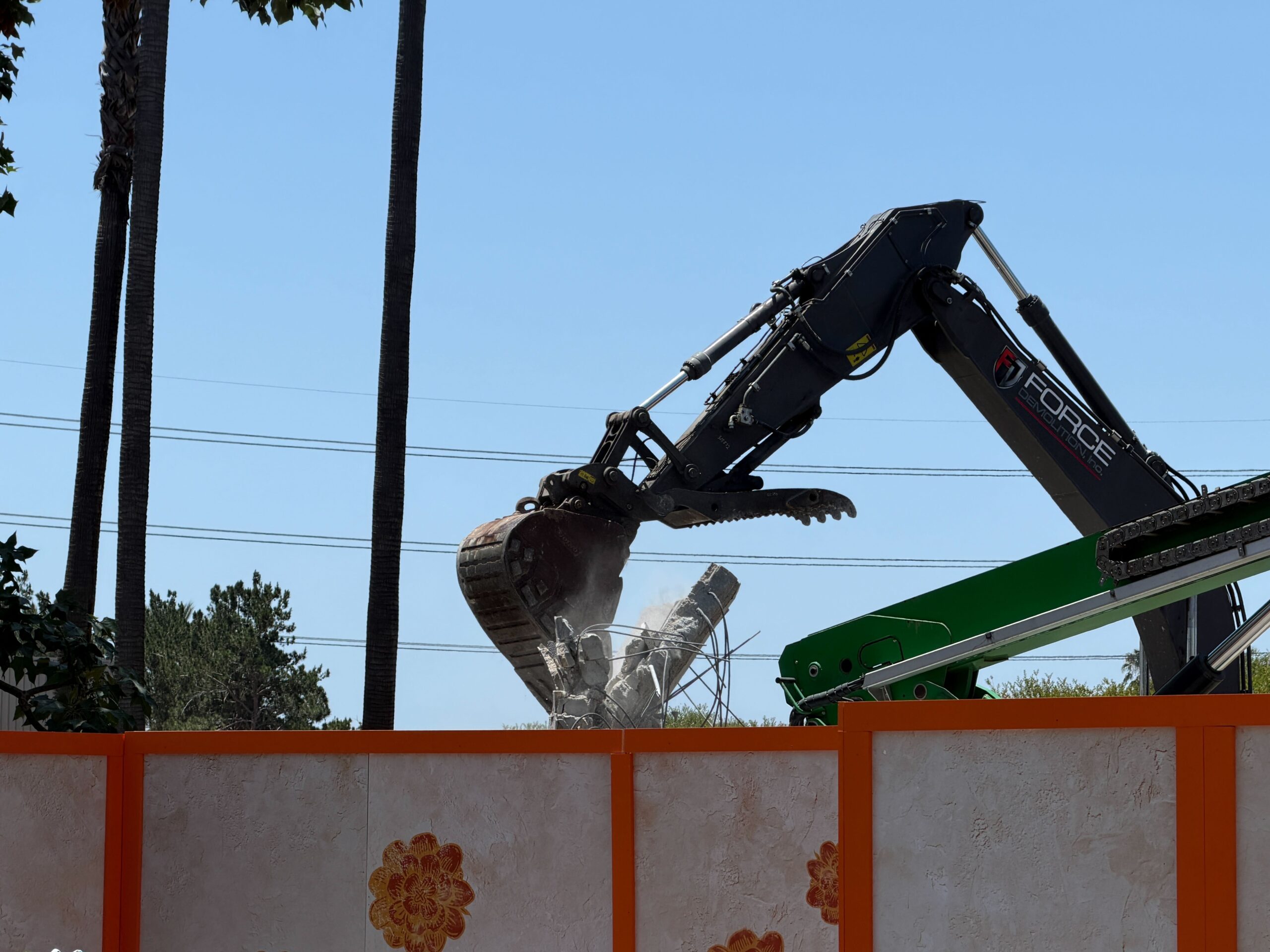 The bucket reached around to the back of the concrete wall and pulled it down, creating a small cloud of dust.