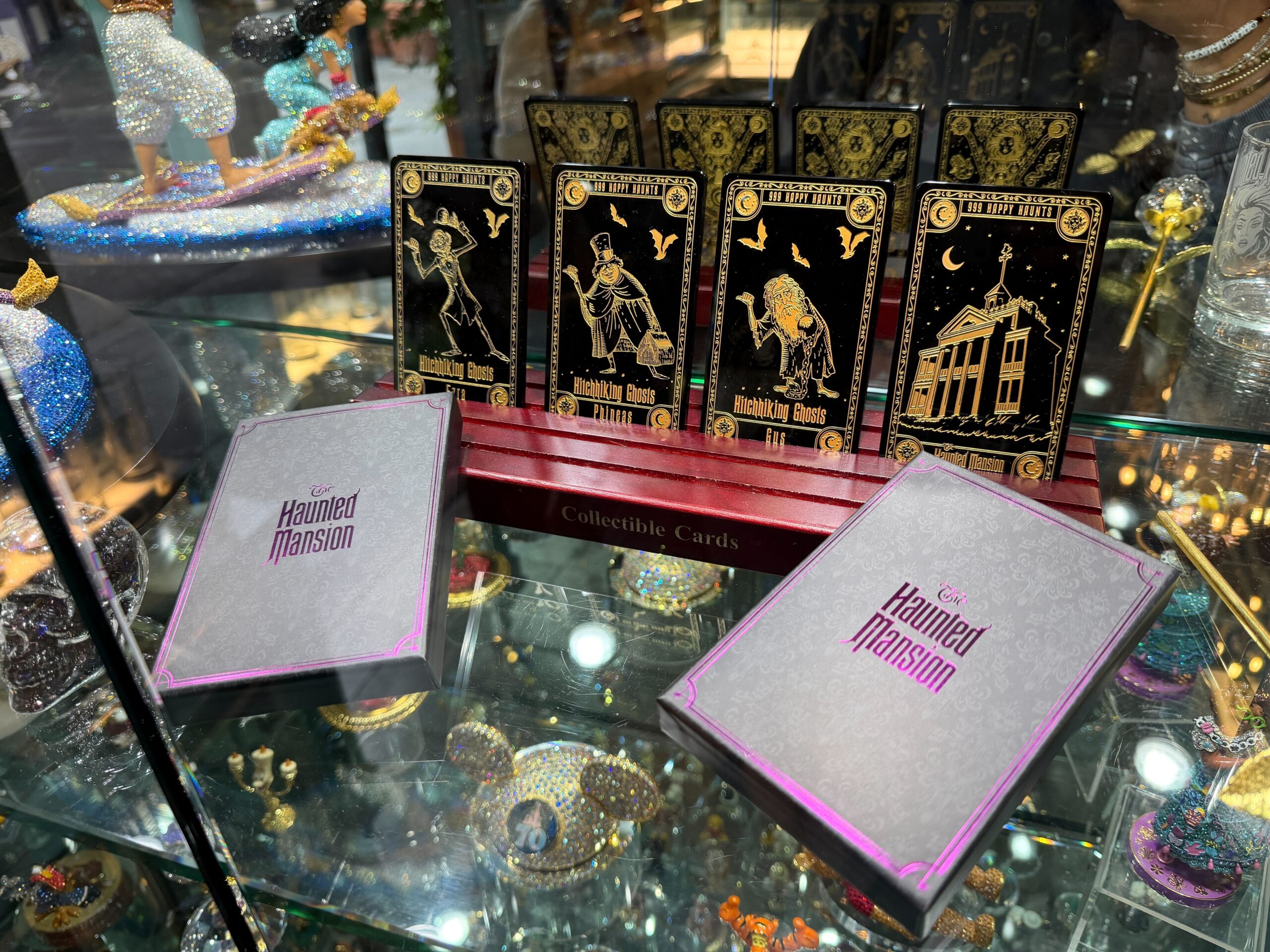 Phineas, Ezra, Gus, and the mansion are featured on the black cards with gold details. "999 Happy Haunts" text is featured on the top, and "Hitchhiking Ghosts" text is on the bottom. Each card also has the name of the ghost.