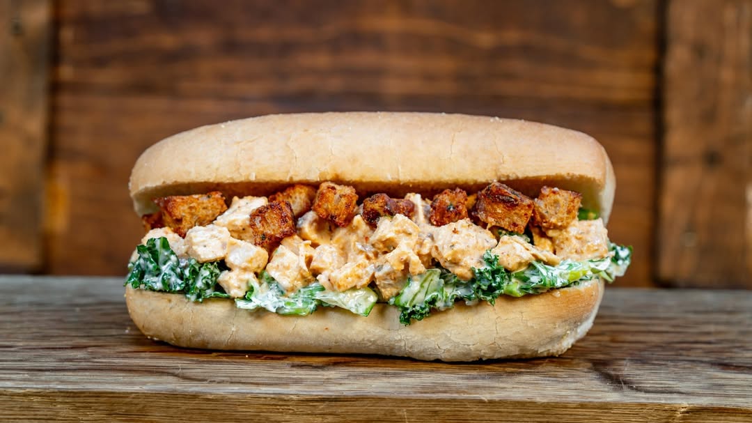 Cajun Caesar Chicken Po’Boy: Kale-romaine mix tossed with house-made Caesar dressing, Cajun chicken, and croutons on a French roll