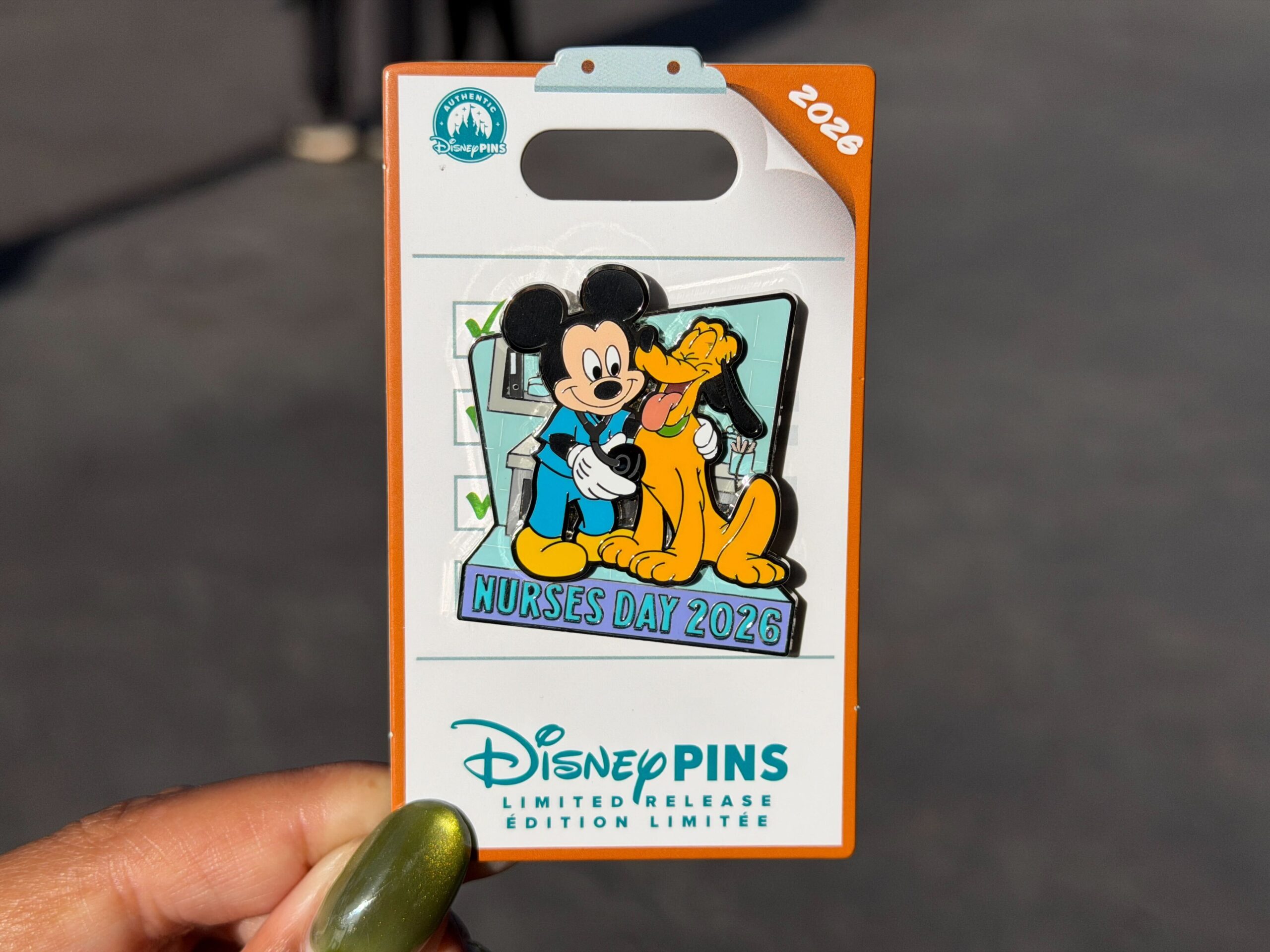 Mickey is pictured in blue nurse scrubs, holding a stethoscope up to Pluto. "Nurses Day 2026" is across the bottom of the pin.