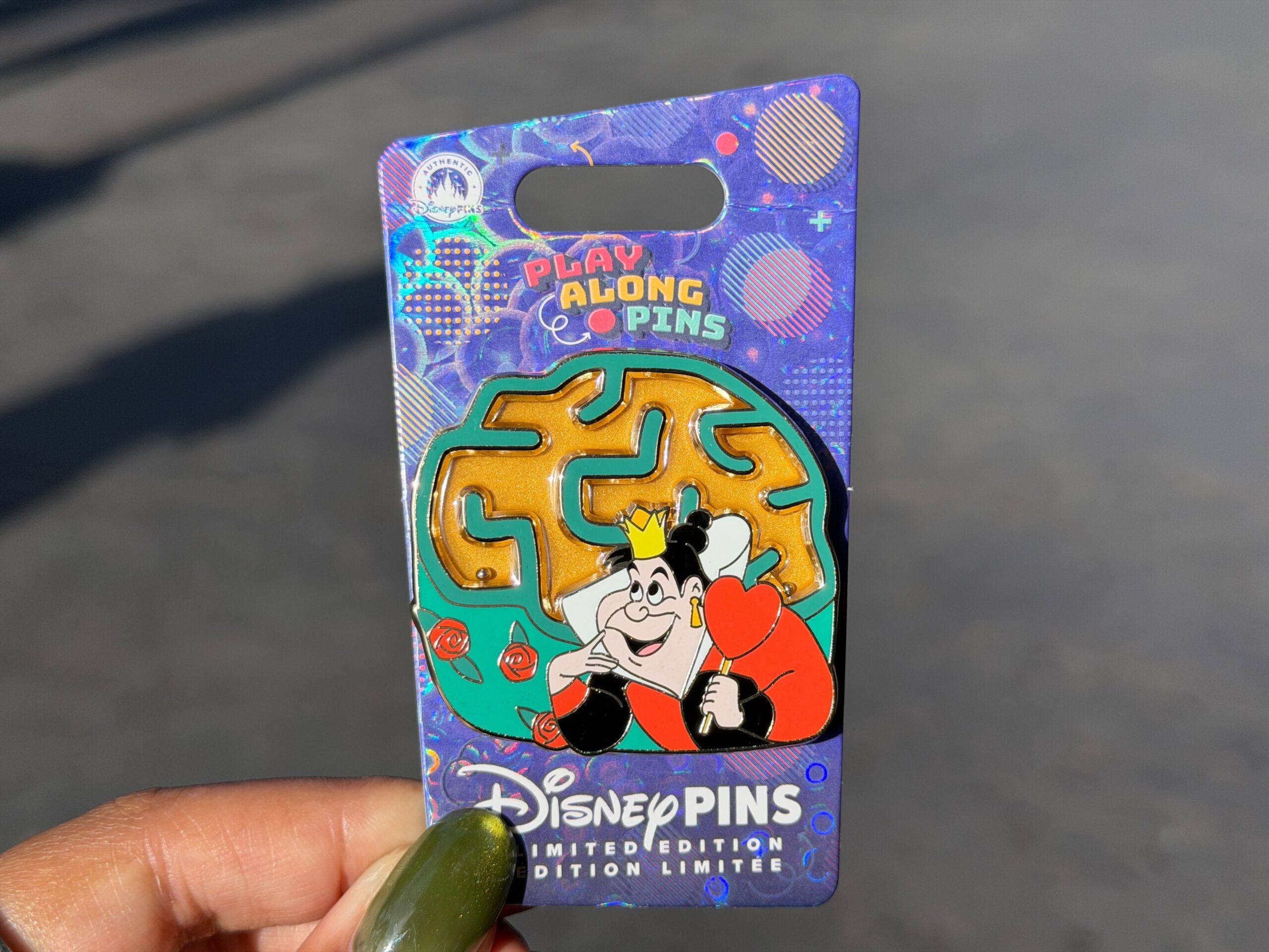 The latest "Play Along" pin features the Queen of Hearts from Alice in Wonderland with a rose bush maze behind her. You can move the pin to roll balls through the maze.