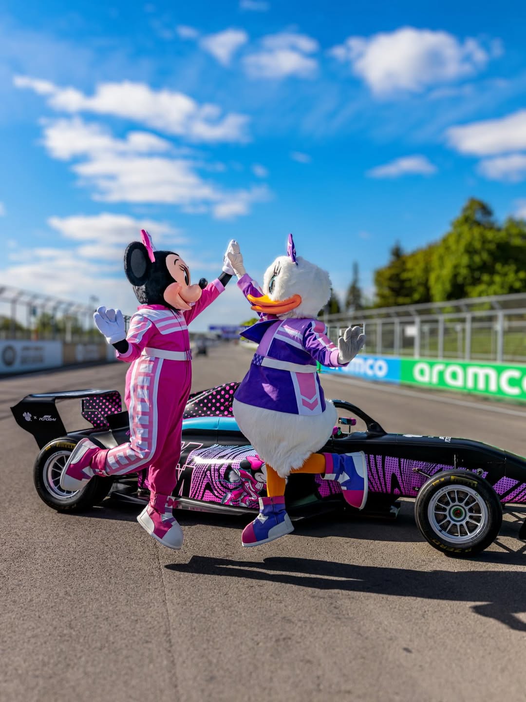 Minnie and Daisy jumping and high fiving on a racetrack in Montreal ahead of Round 2 of F1 Academy.