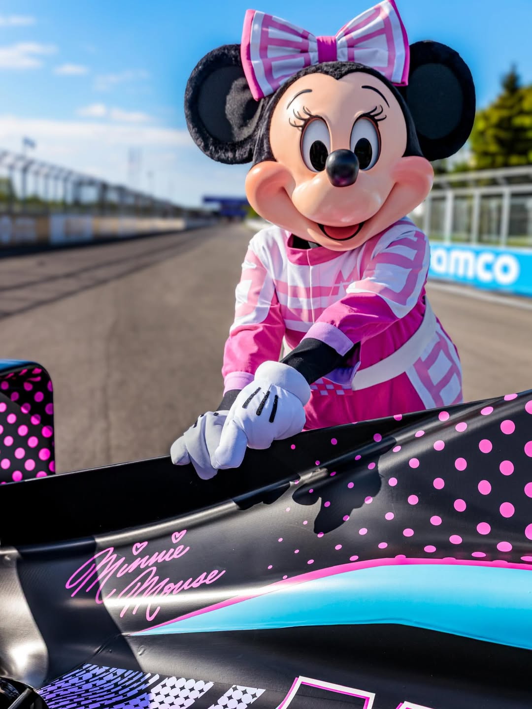 Minnie pointing to her signature printed on her vehicle.