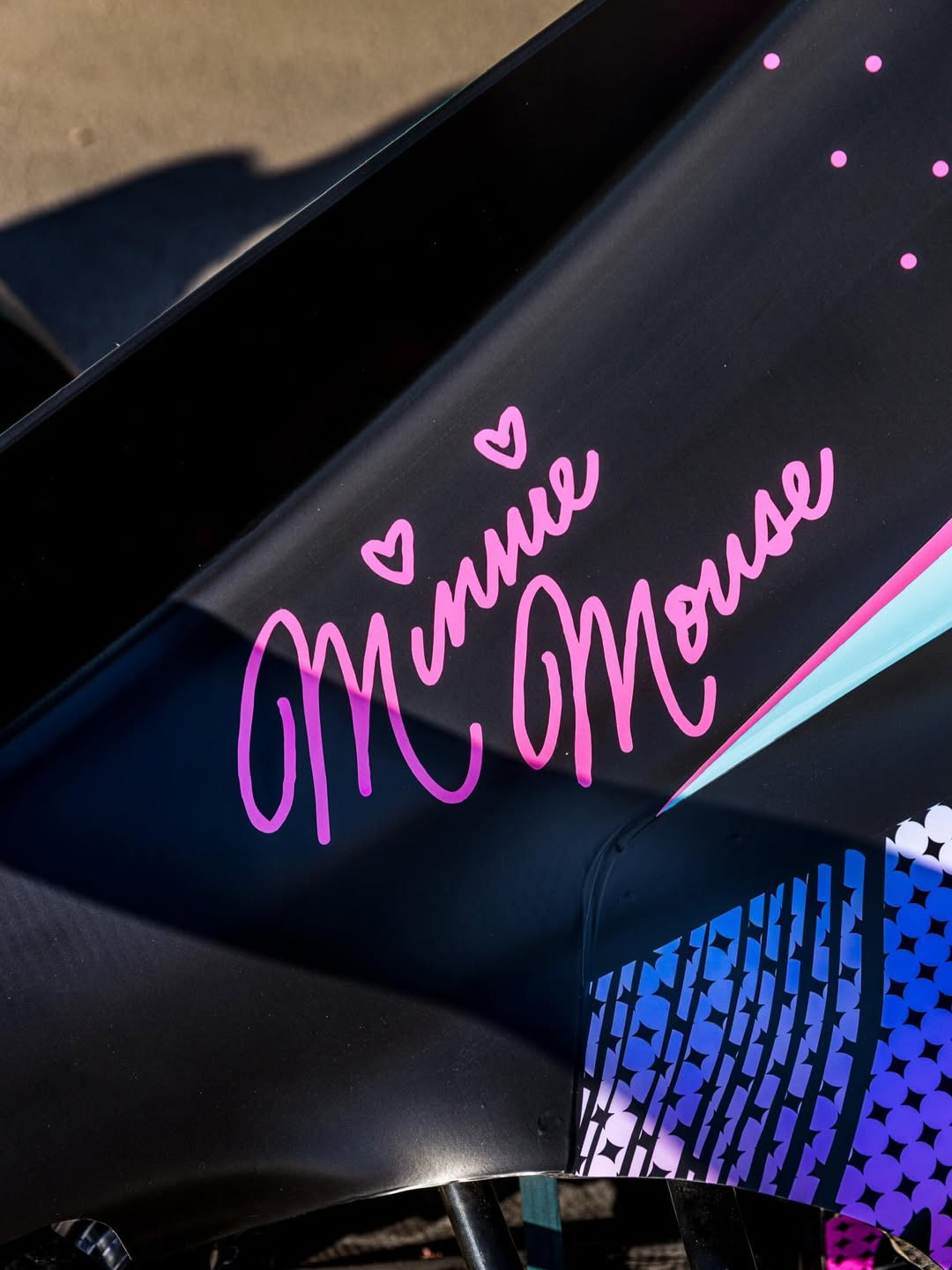 Minnie Mouse's pink cursive signature on the vehicle.