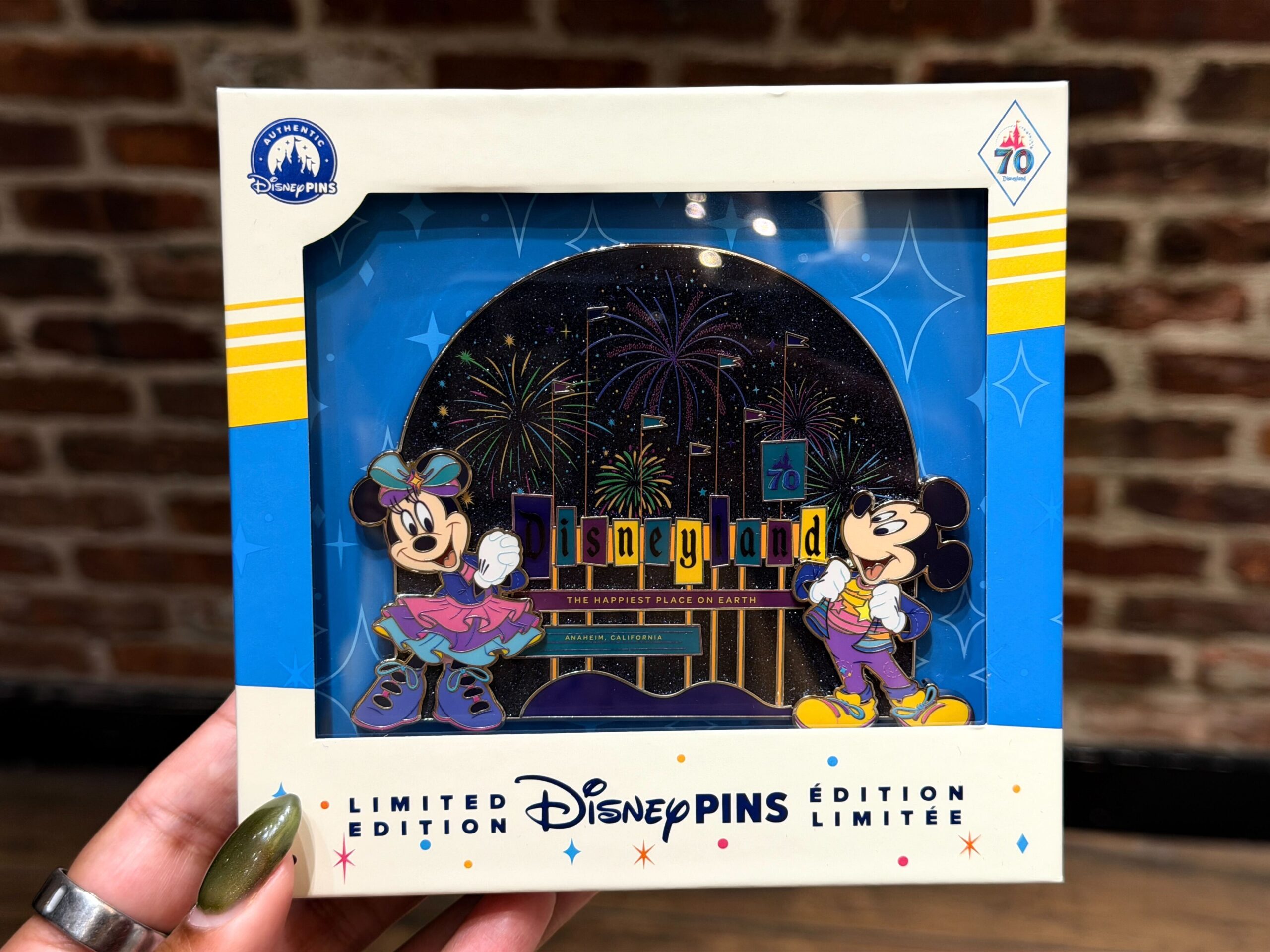 This jumbo pin shows Minnie and Mickey standing on either side of the Disneyland sign. The night sky is bursting with colorful fireworks and both characters are wearing their vivid celebratory outfits.