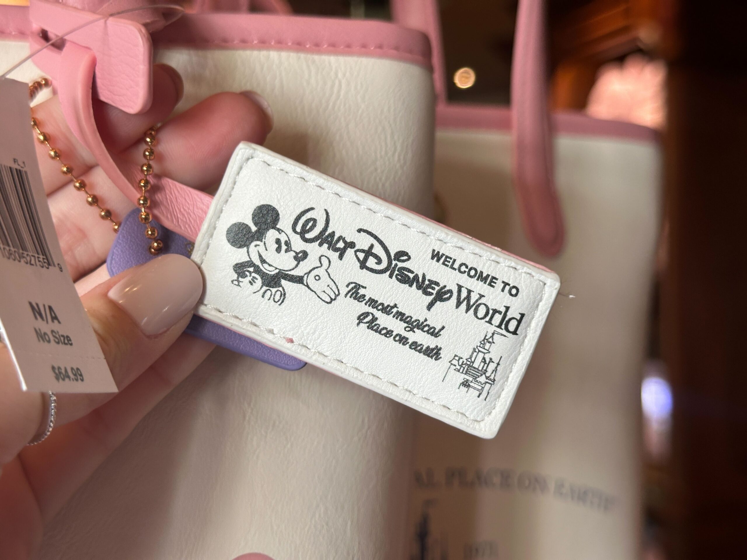 There is a retro hangtag attached to the front strap with Mickey in black and white with the Disney World wordmark and the words "Welcome to Walt Disney World the Most Magical Place on Earth." Another hangtag, this one purple, is also attached with a Disney Parks wordmark.