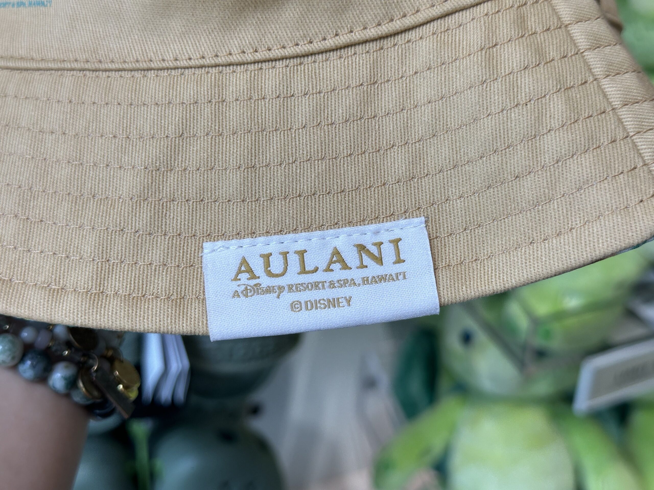 The beige bucket hat has the signature structures of Aulani in blue and pink. There is an Aulani tag at the bottom. Inside, Duffy and Friends are patterned all-over in the same colors for this collection.