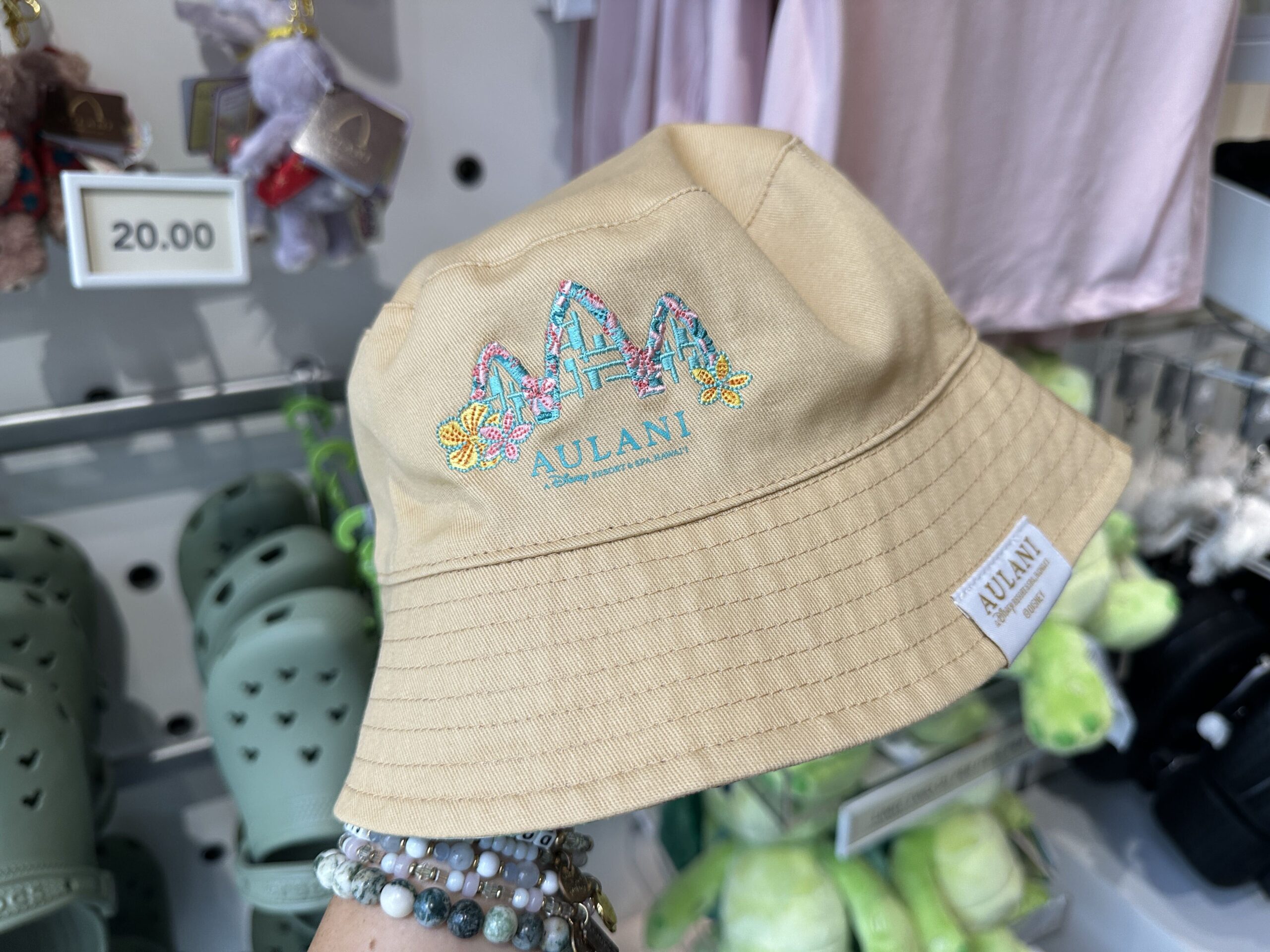 The beige bucket hat has the signature structures of Aulani in blue and pink. There is an Aulani tag at the bottom. Inside, Duffy and Friends are patterned all-over in the same colors for this collection.